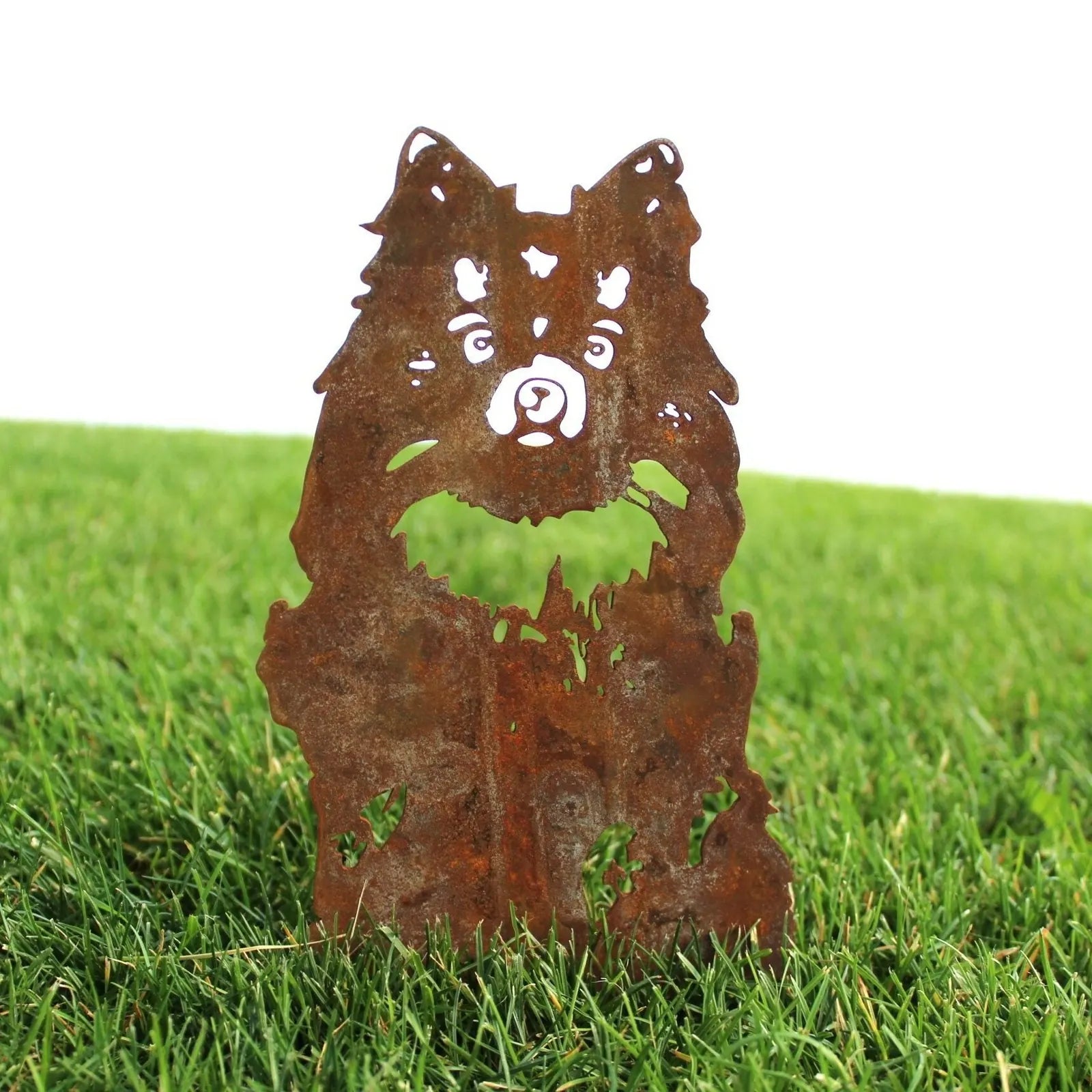 Rusty Corten steel Pomeranian silhouette against green grass, adding rustic charm to outdoor dog decor.