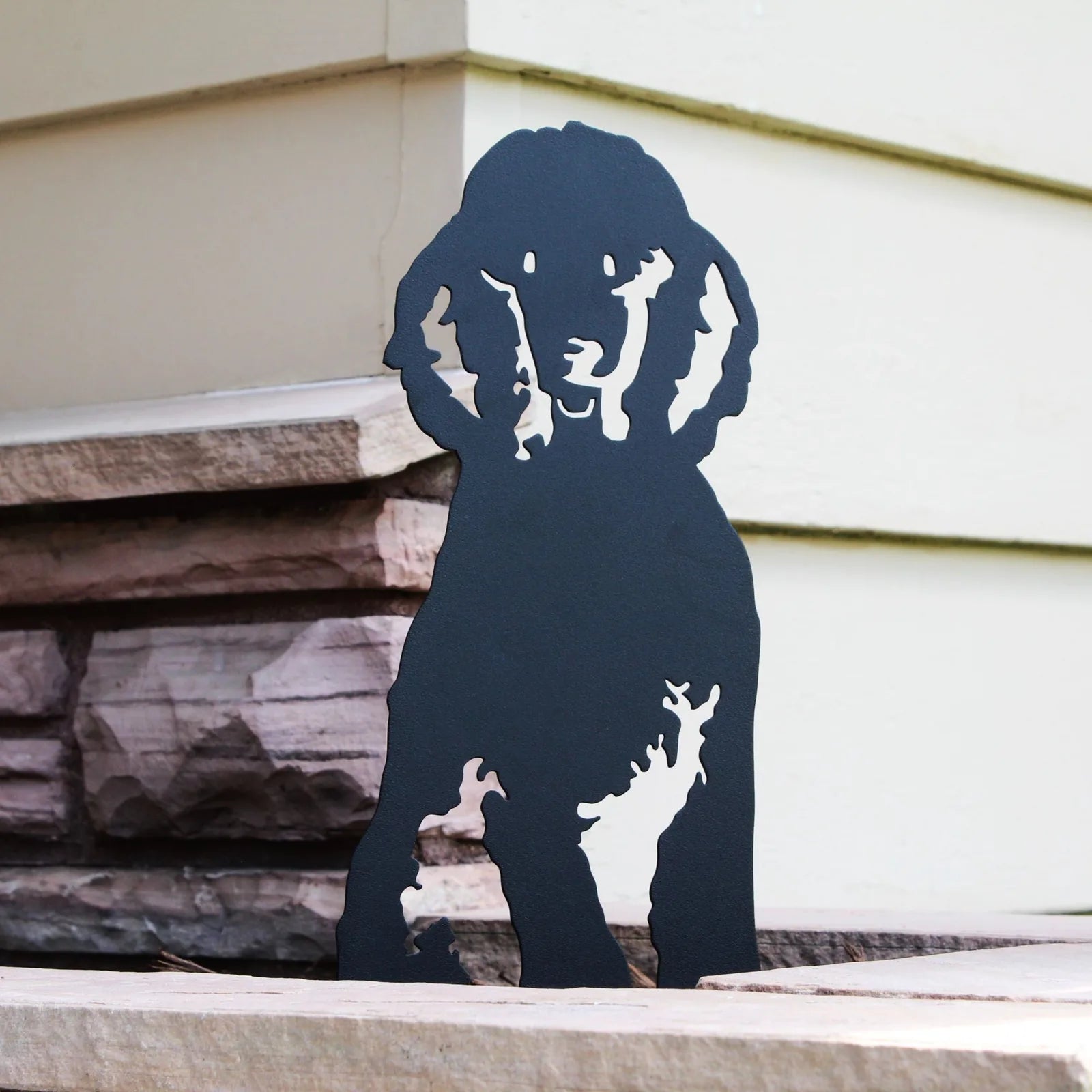 Black metal silhouette of a poodle dog, showcasing detailed features, ideal for outdoor decor and garden displays.