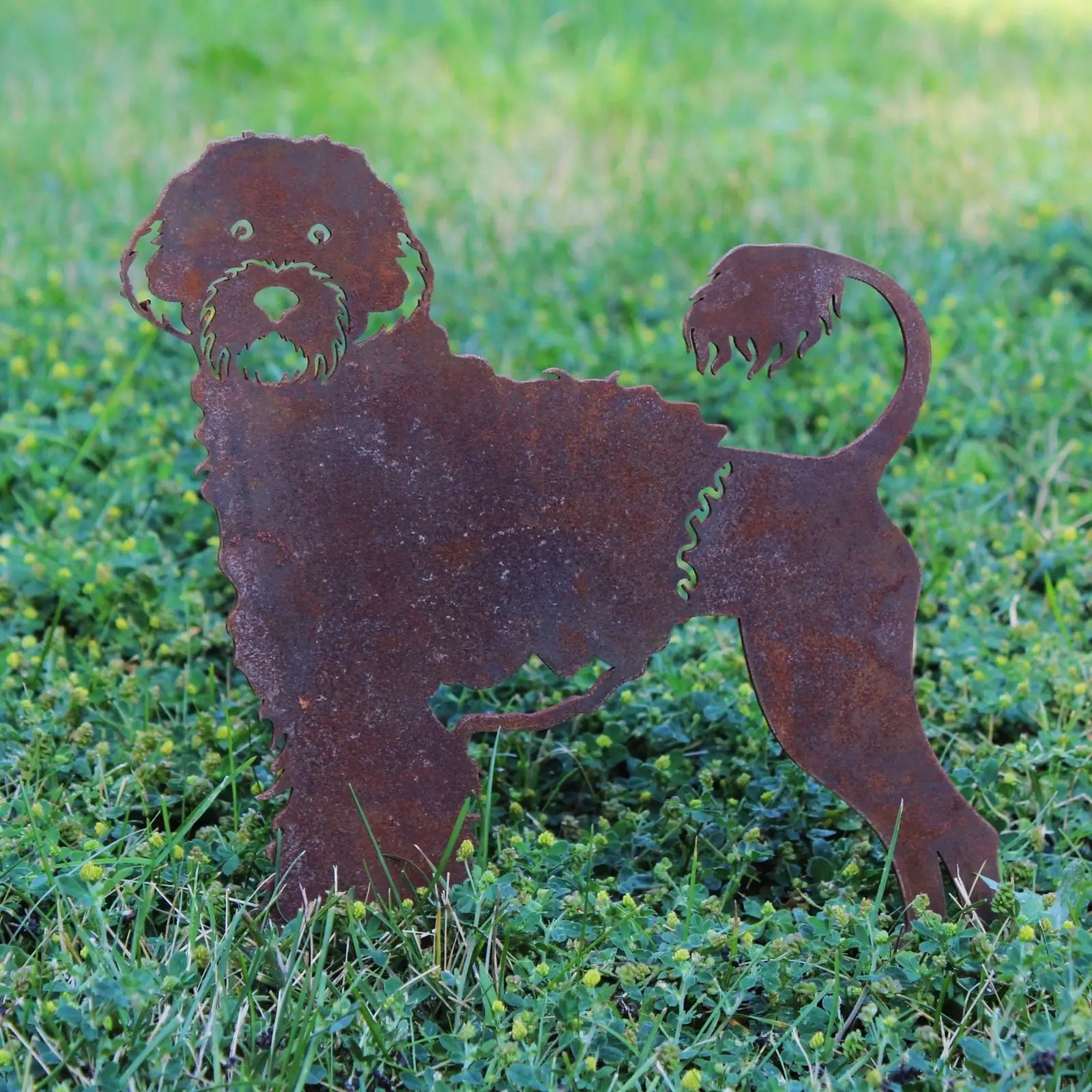 Rust-colored metal silhouette of a Portuguese Water Dog standing on green grass, showcasing intricate detailing.