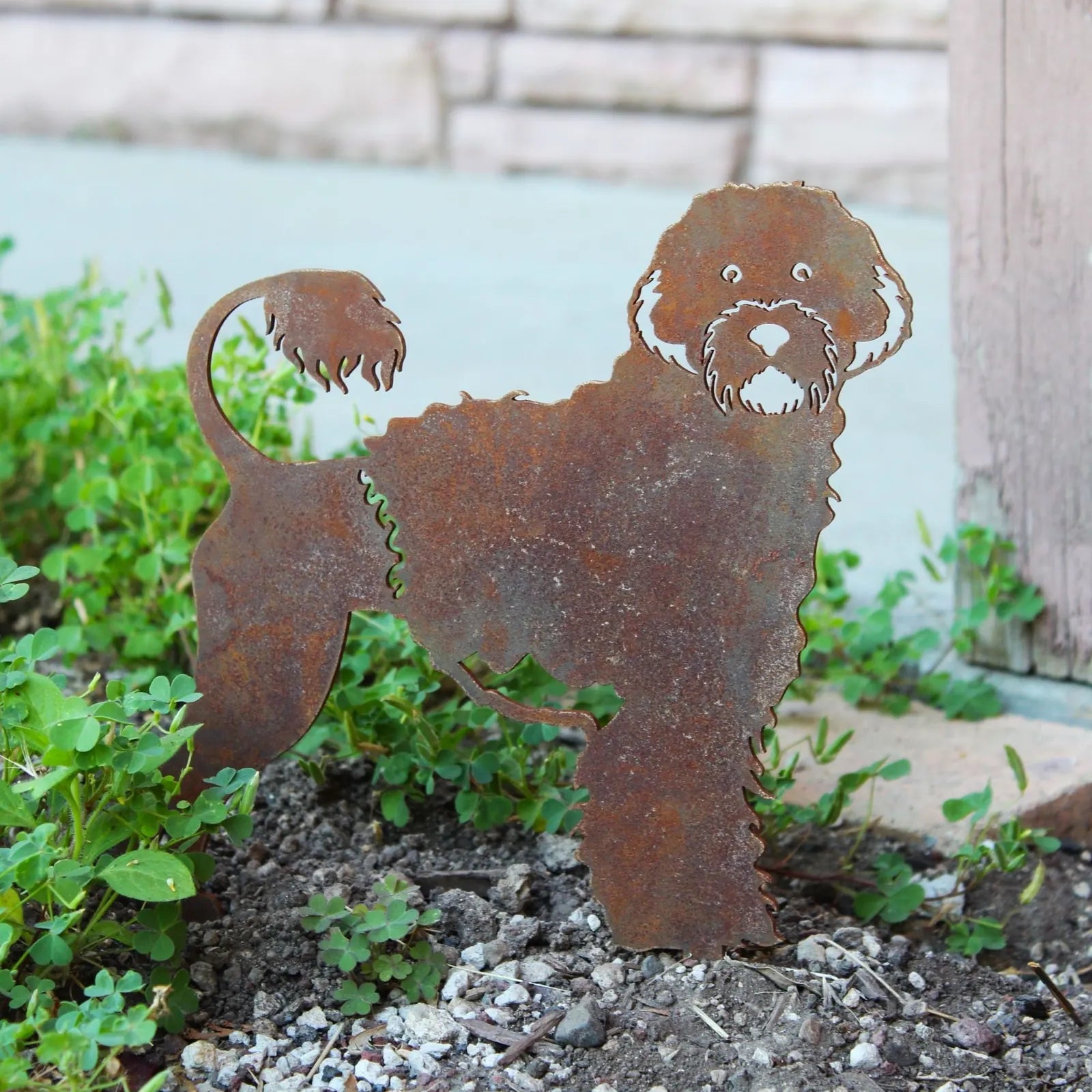 Rusty metal silhouette of a Portuguese Water Dog stands among greenery, showcasing intricate details and a playful design.