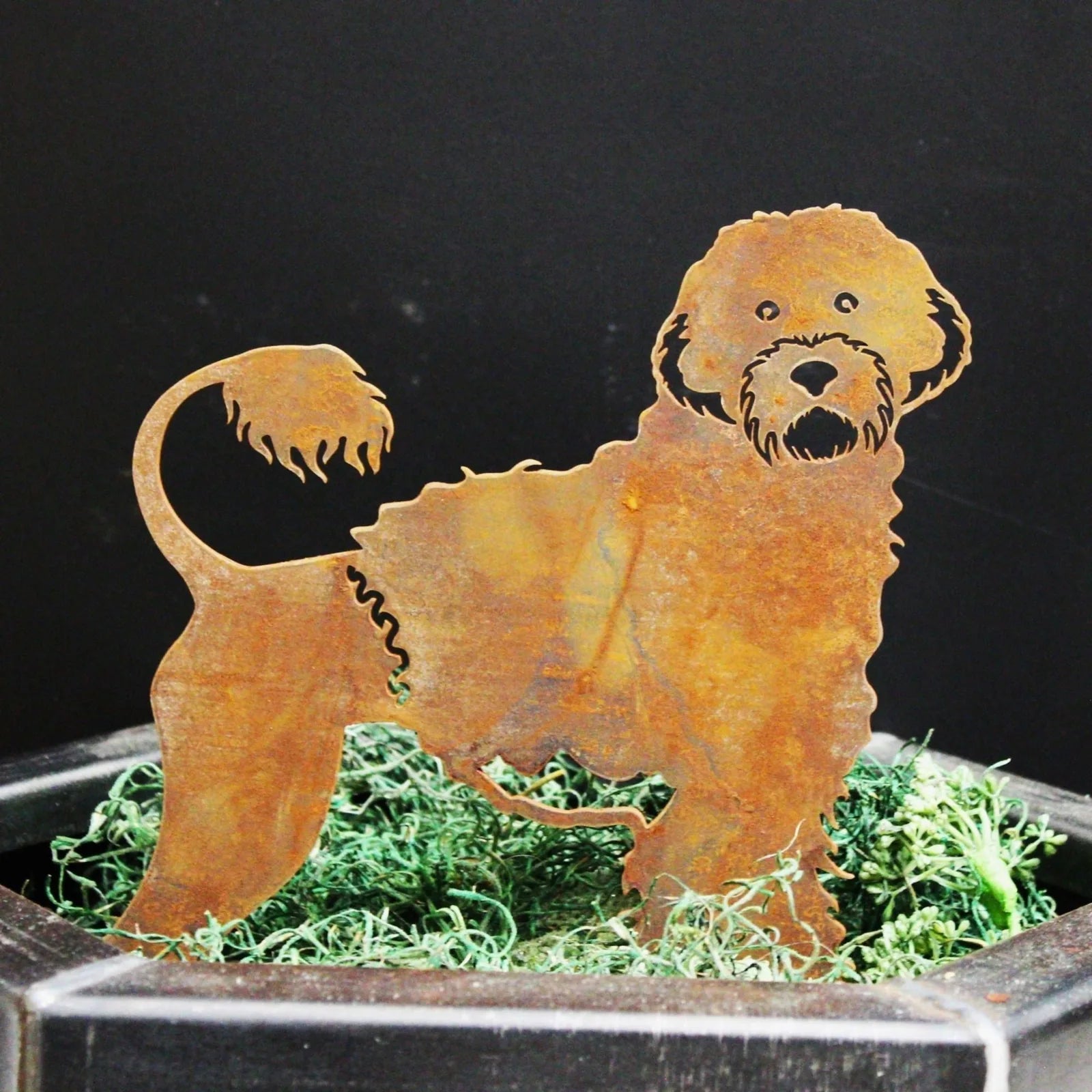 Rusty Corten steel silhouette of a Portuguese Water Dog with intricate details, displayed among green moss decor.