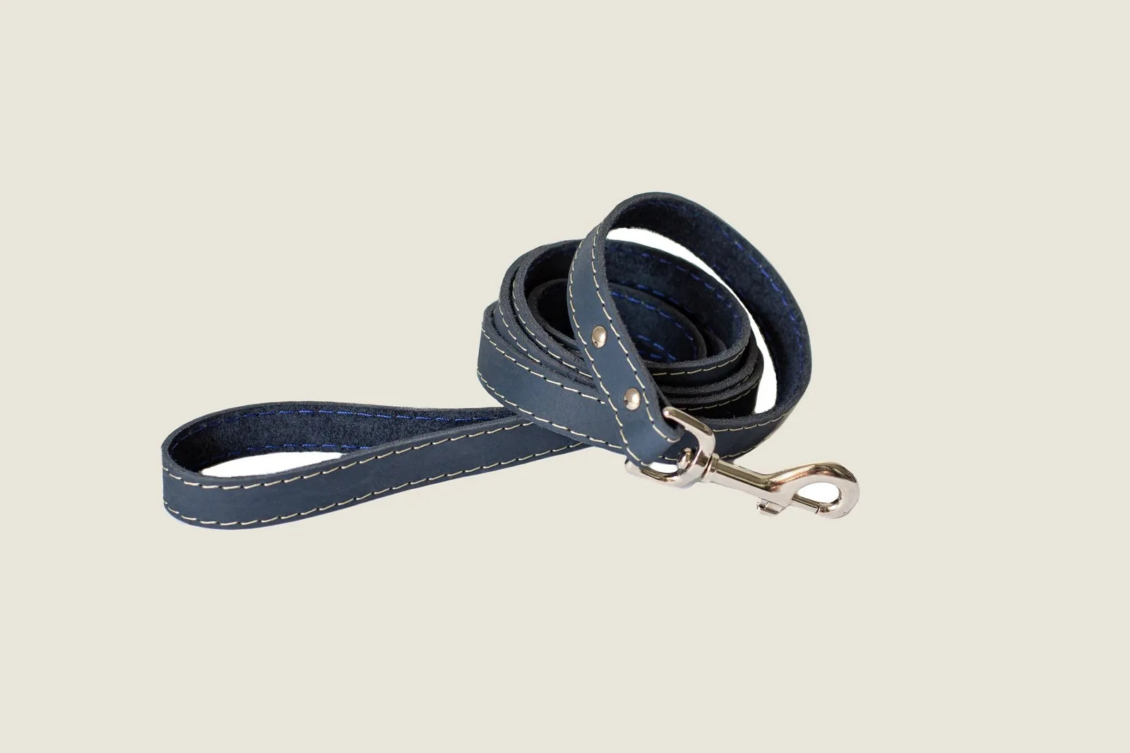 Blue leather dog leash with white stitching, featuring a durable metal clip, coiled neatly for easy storage.