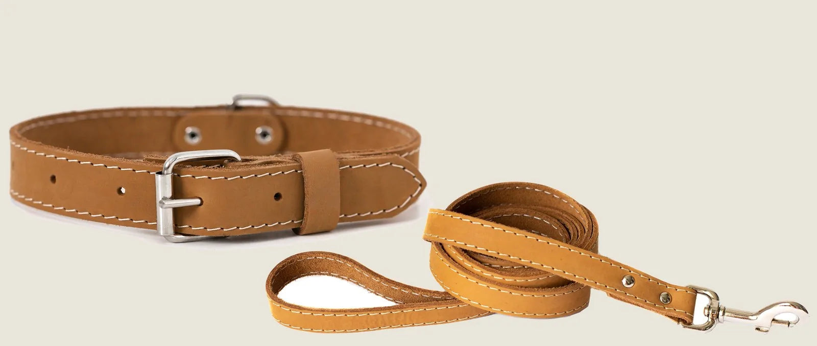 Soft tan leather collar and leash set with white stitching and metal hardware, ideal for stylish dog walks.