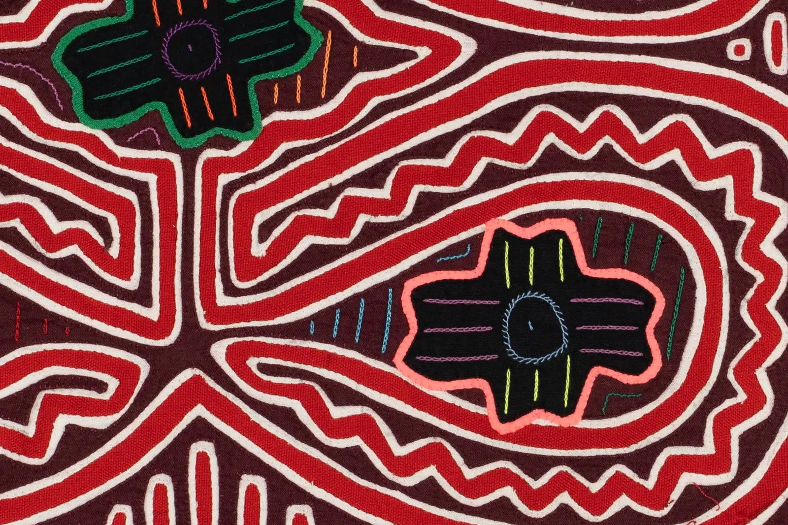Hand-stitched Mola textile featuring vibrant red and black designs with intricate geometric patterns on a maroon background.