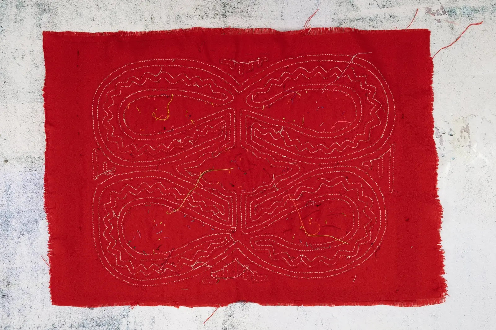 Hand-stitched red Mola tapestry featuring intricate white geometric patterns, crafted by indigenous artisans in Panama.