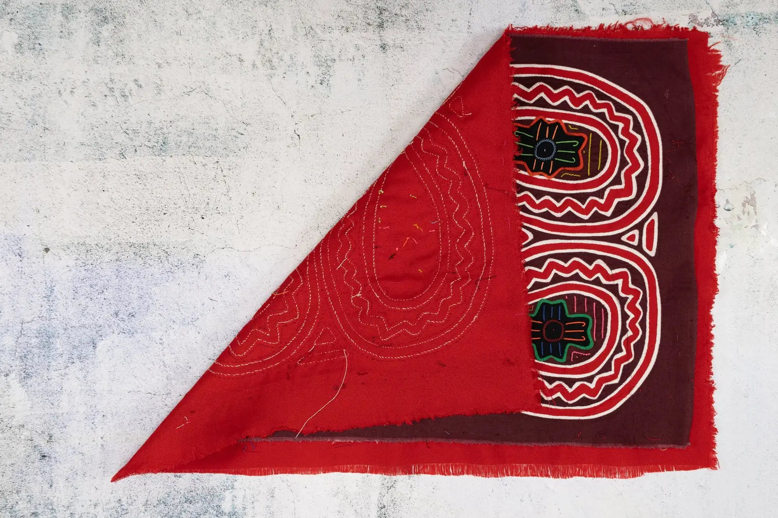 Hand-stitched red and brown Panama Mola tapestry featuring geometric patterns and vibrant designs. Unique textile art.