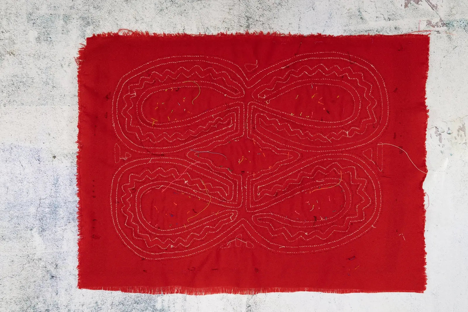 Vibrant red hand-stitched Mola featuring intricate white geometric patterns, showcasing traditional Panama textile artistry.