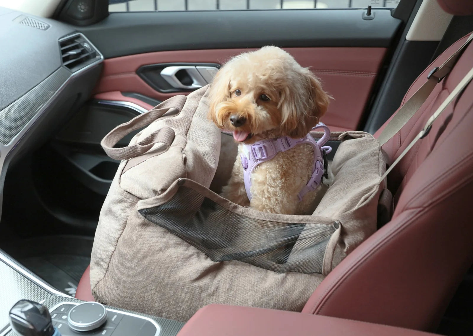 Cozy pink puff guard dog car seat with a small dog in a harness, set in a luxury vehicle interior.