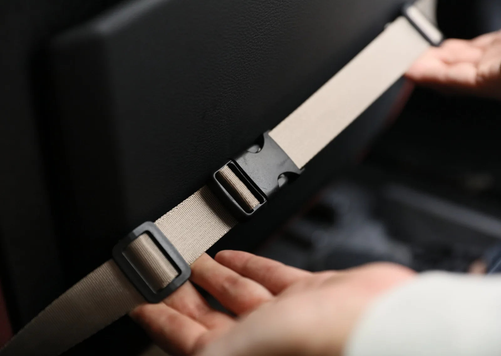 Securely fastening a beige car seat belt to the black seat back, demonstrating safety for the Puff Guard Dog Car Seat.