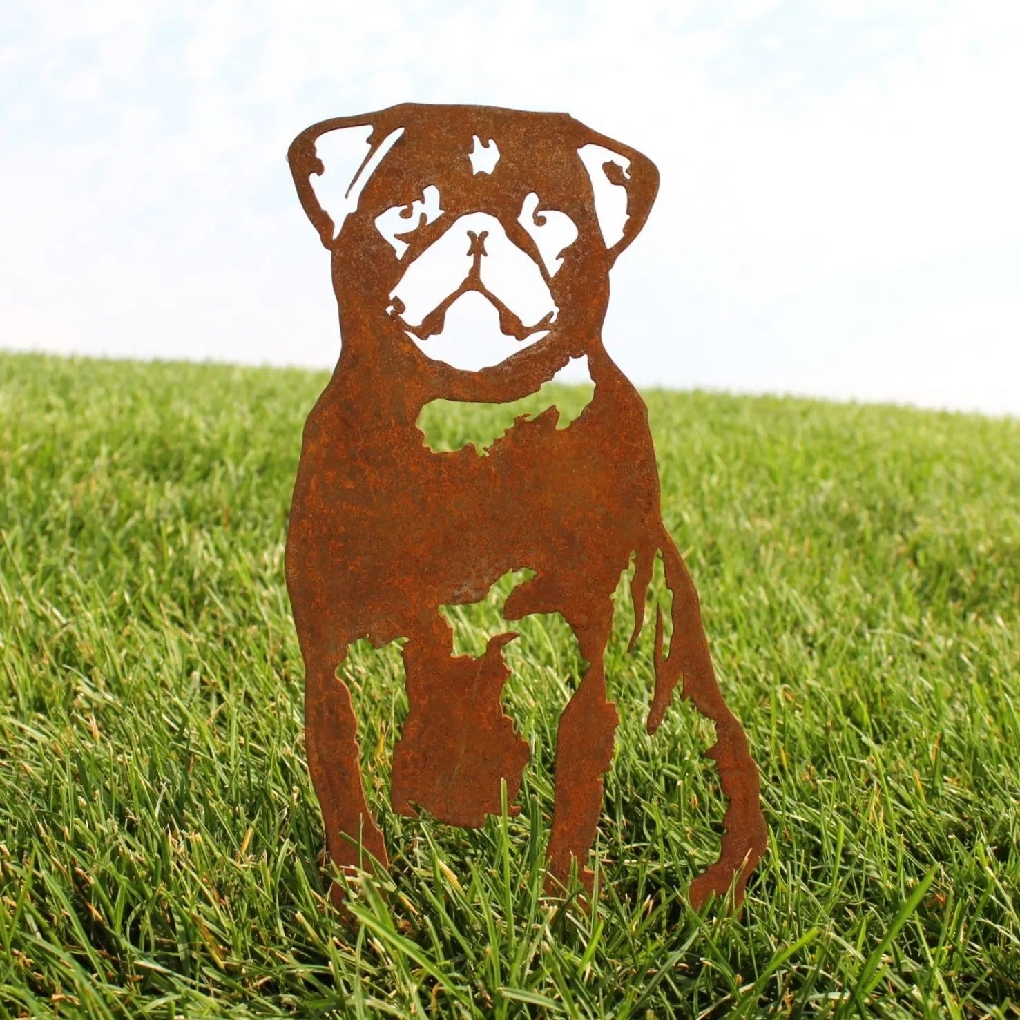 Rusty metal silhouette of a pug standing on green grass, showcasing handmade Corten steel design for outdoor decor.