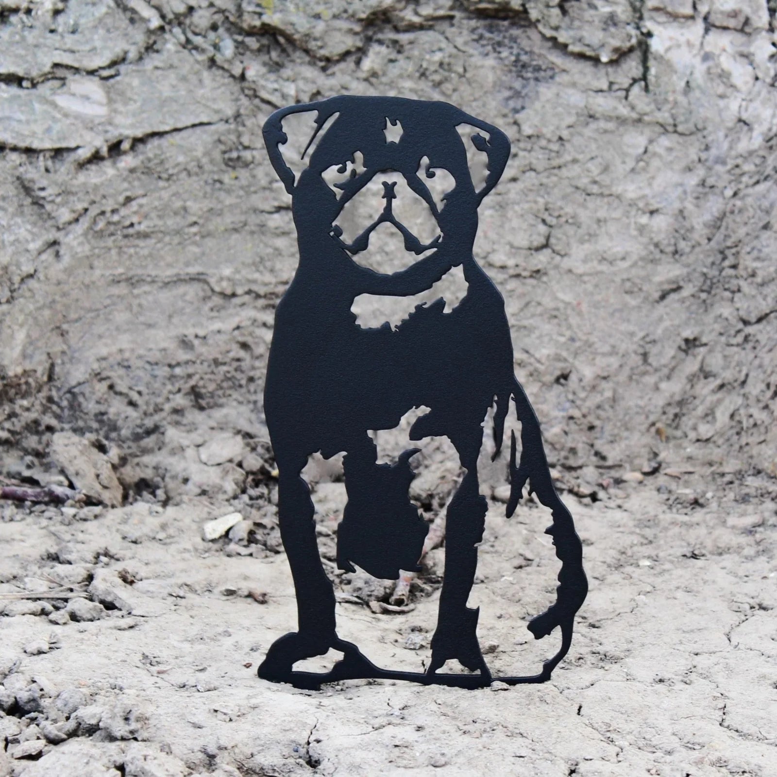 Black metal silhouette of a pug standing on a textured gray surface, showcasing intricate cutout details.