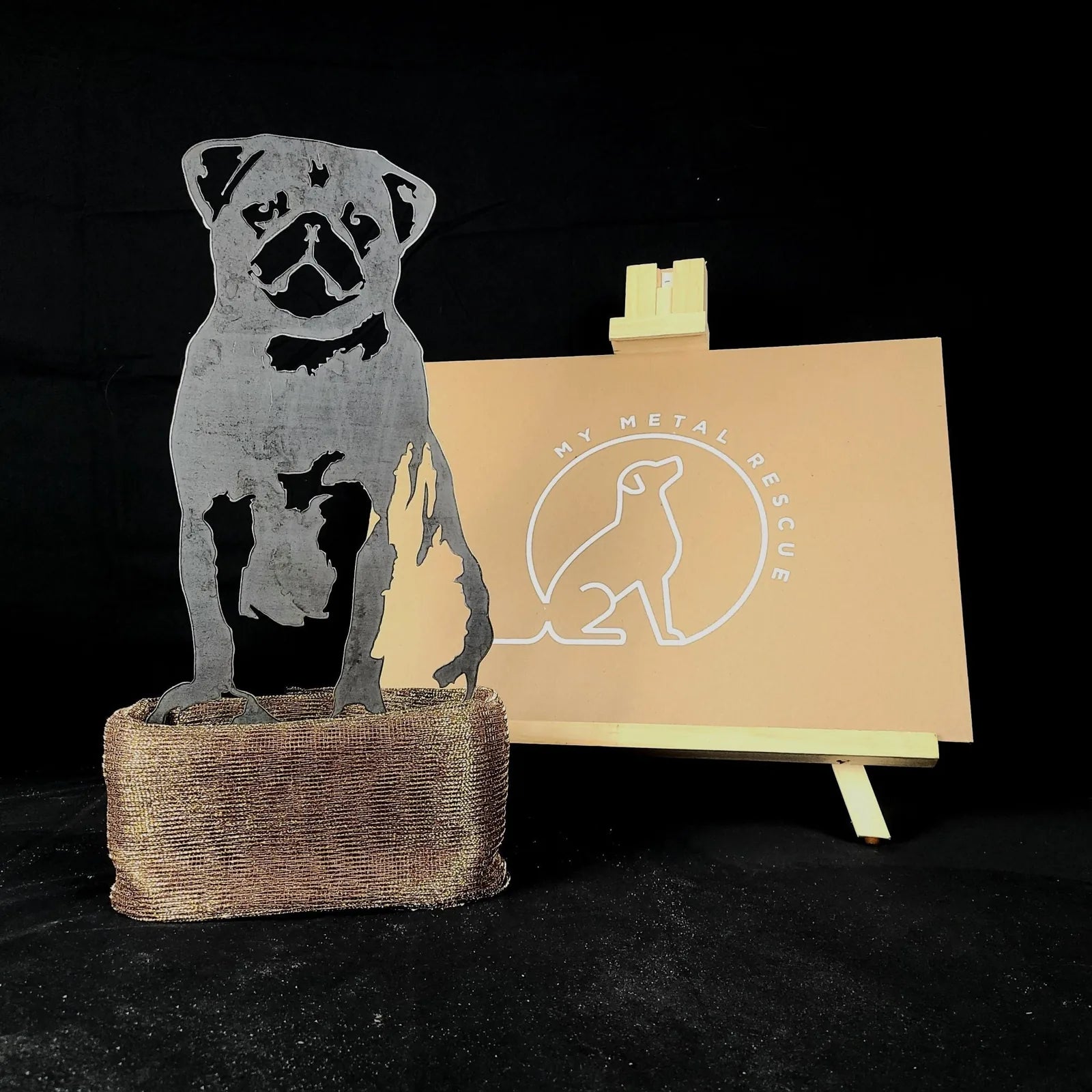 Pug silhouette in black metal with a textured base, showcasing My Metal Rescue’s logo on a light backdrop.