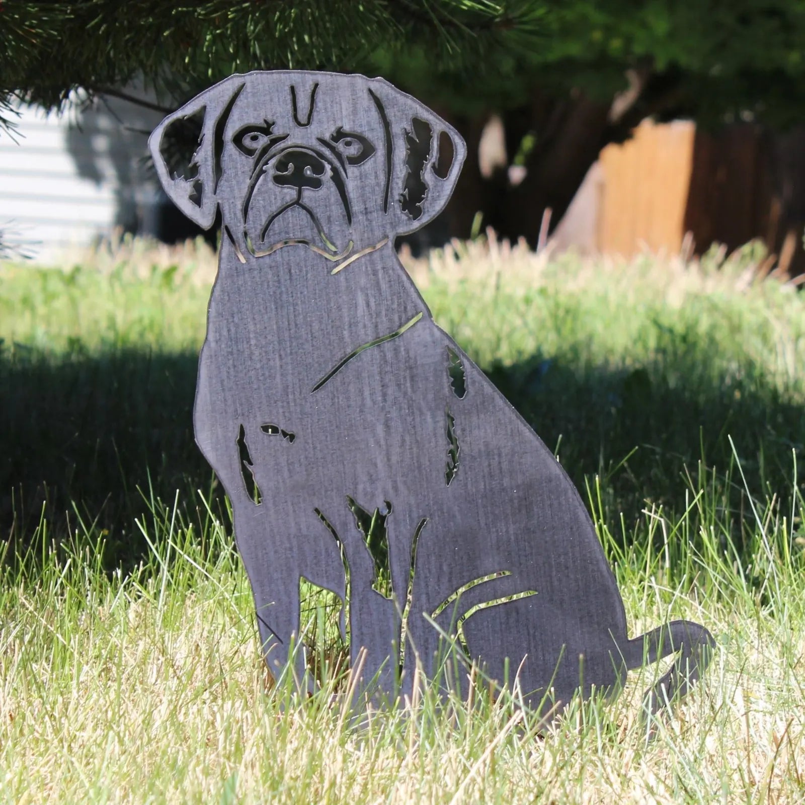 Black metal silhouette of a Puggle dog, sitting on grass, showcasing intricate cut-out details and a weathered texture.