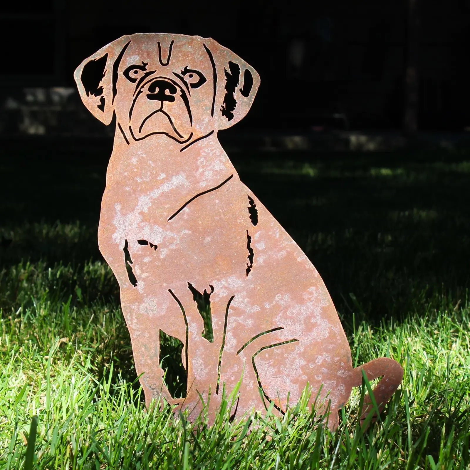 Handmade Corten steel Puggle silhouette standing on grass, showcasing a rust patina and intricate cut-out design.