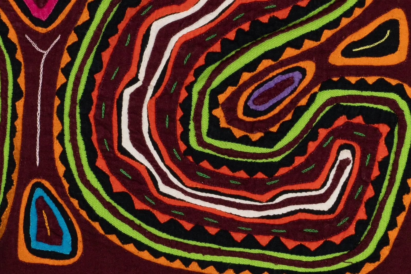 Vibrant hand-stitched Mola tapestry featuring swirling patterns in red, green, orange, and black.