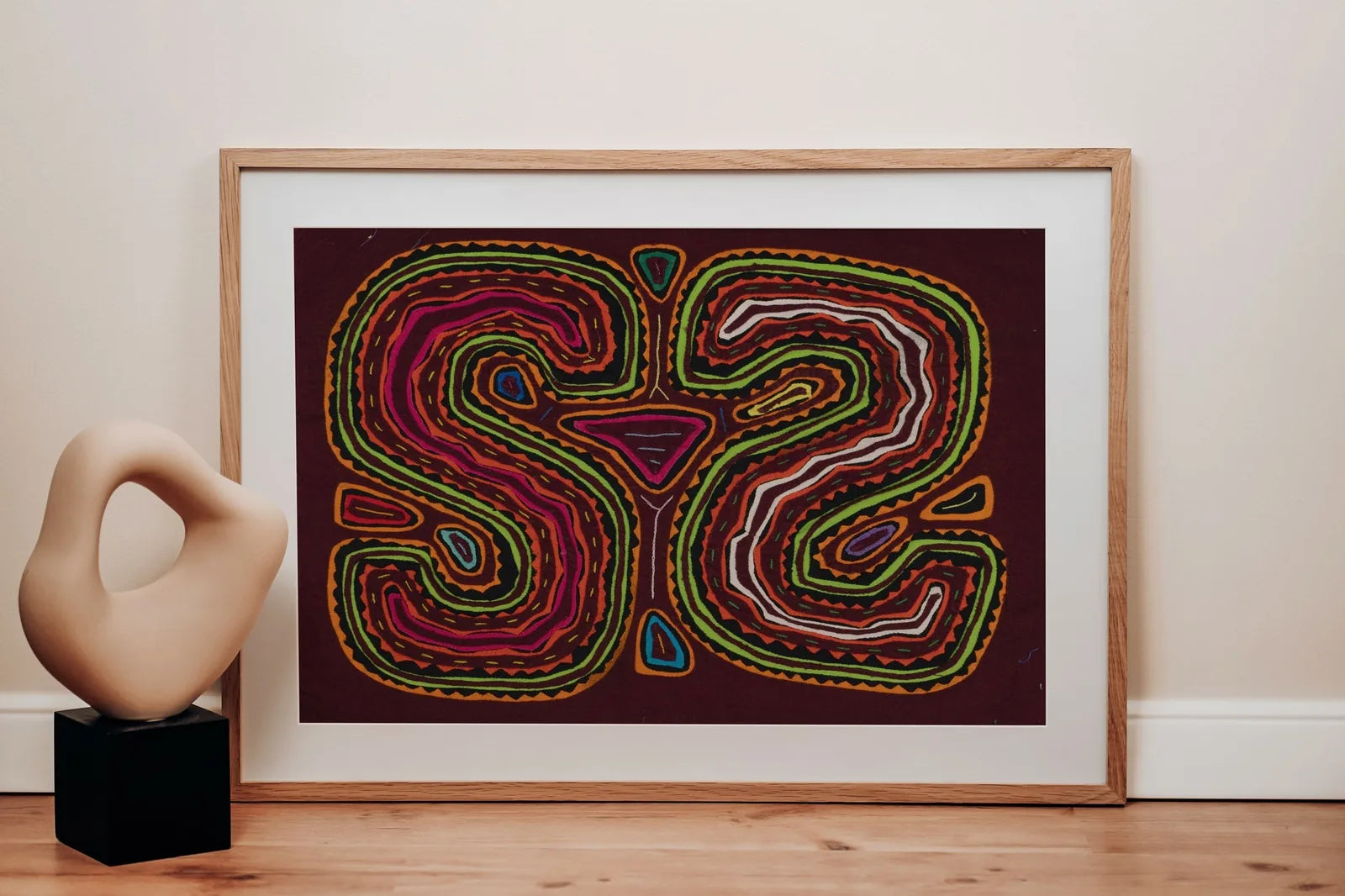 Colorful hand-stitched Mola tapestry featuring an optical illusion dog face design, framed against a neutral wall.