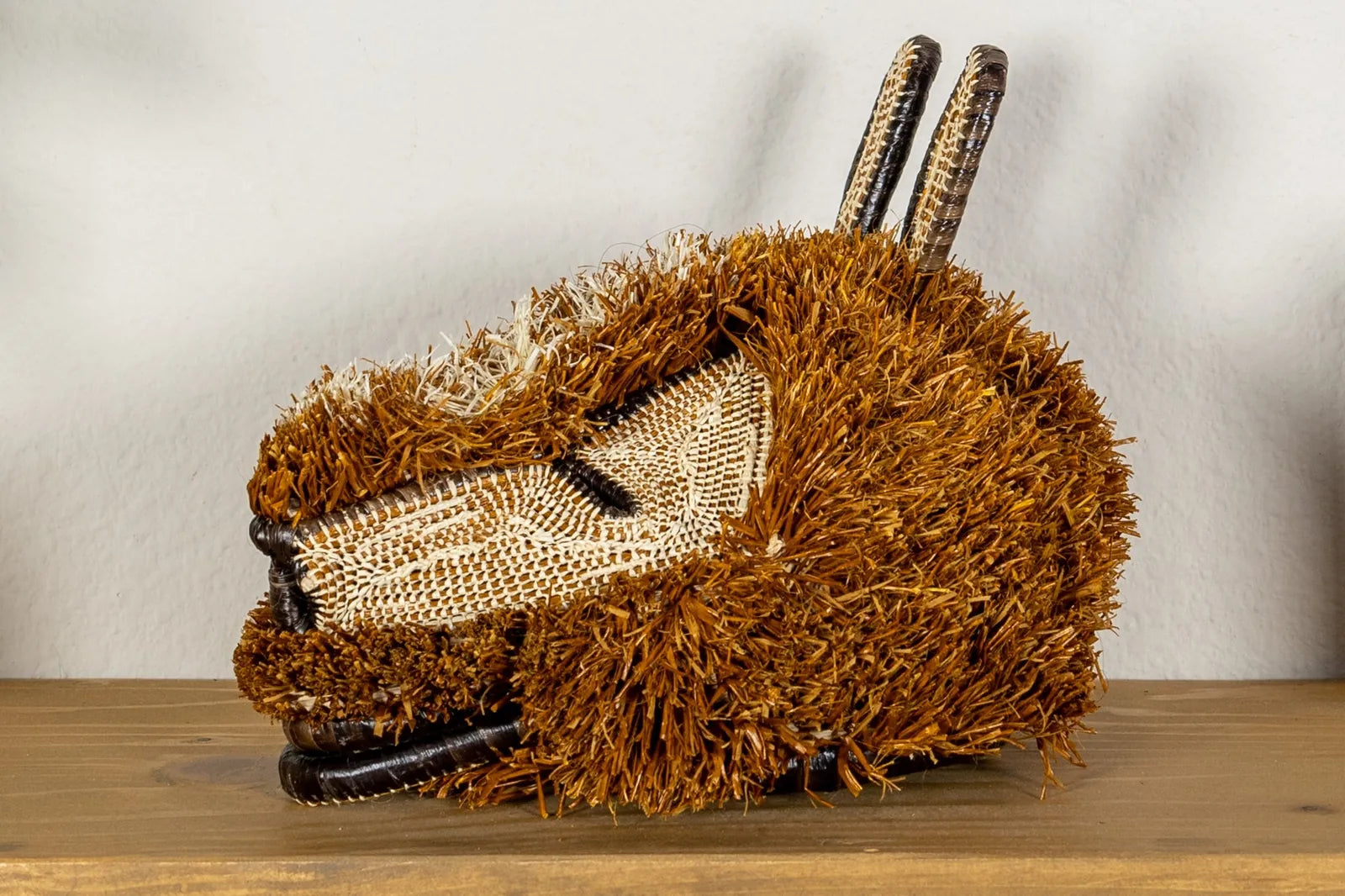 Handwoven puppy dog mask in earthy brown tones, featuring intricate traditional designs, made from natural materials.