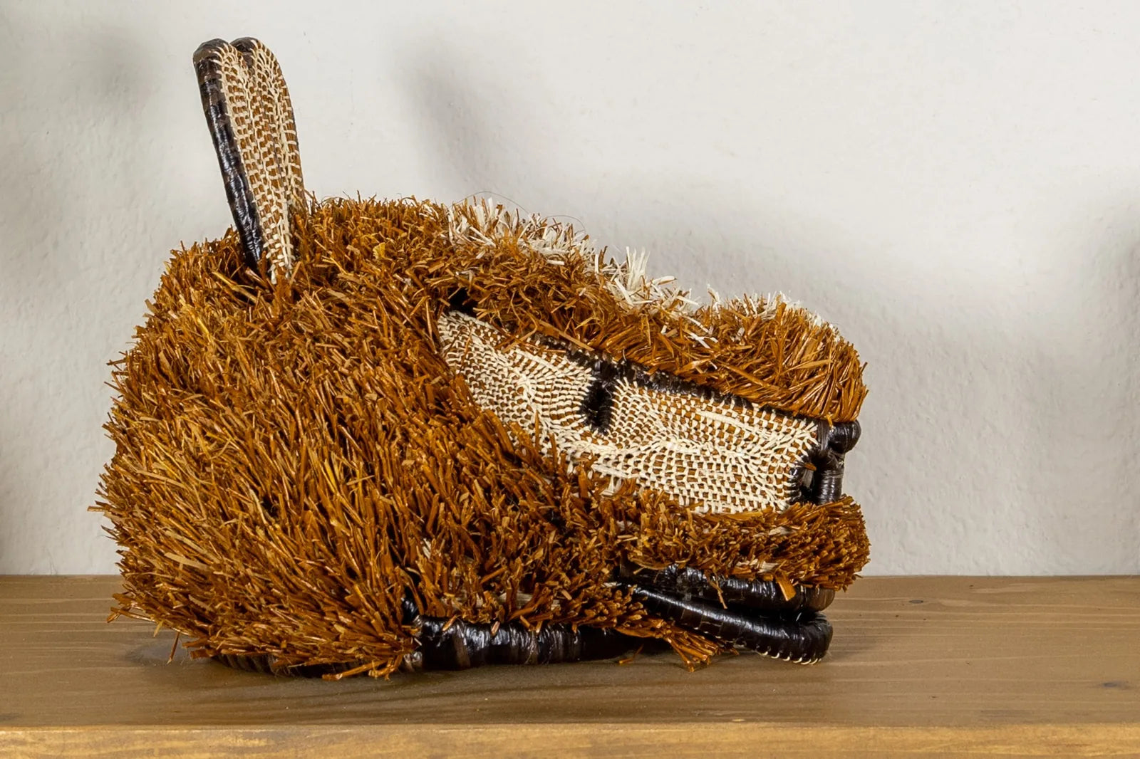 Handwoven puppy dog mask in earthy browns, showcasing intricate coil weaving and natural textures, perfect for wall decor.