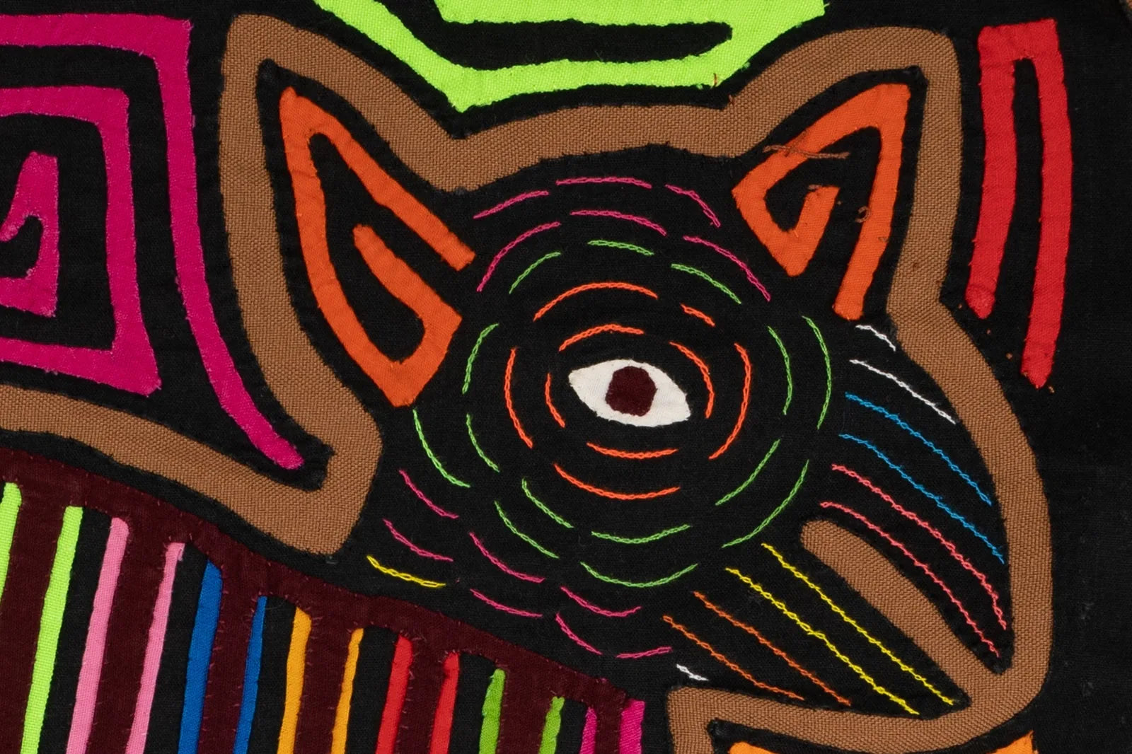Colorful hand-stitched Panama Mola featuring a stylized dog design in vibrant threads on a dark background.