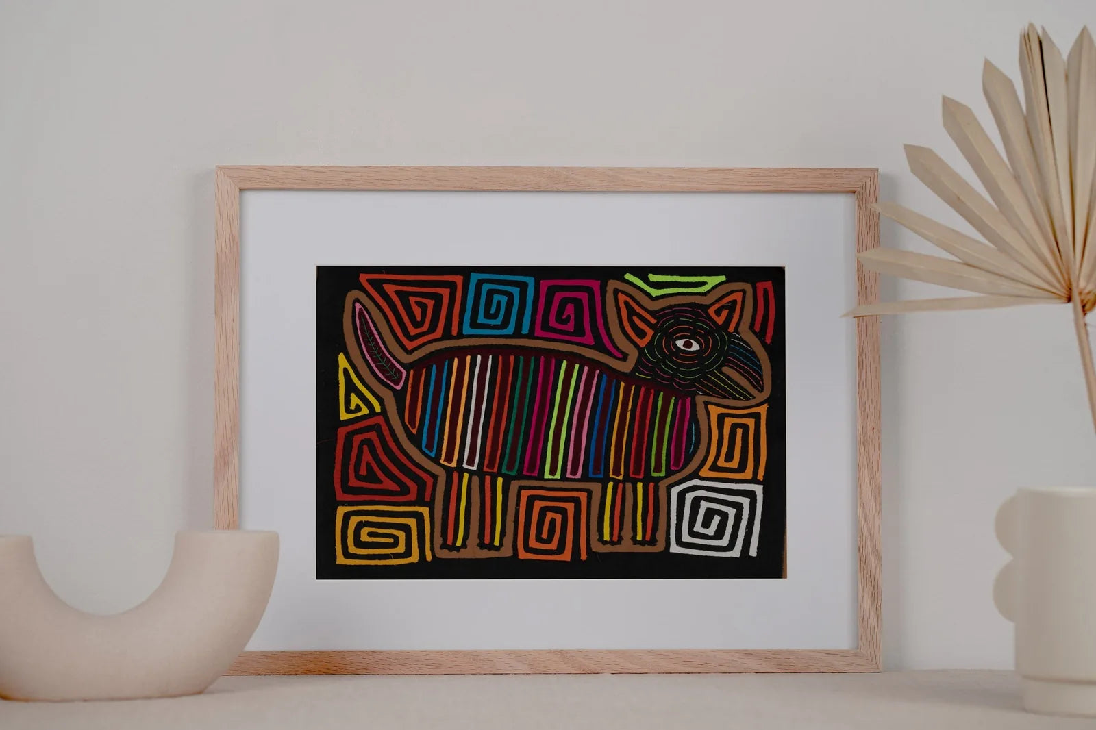 Colorful hand-stitched Mola featuring a stylized dog design with vibrant lines and geometric patterns on a dark background.