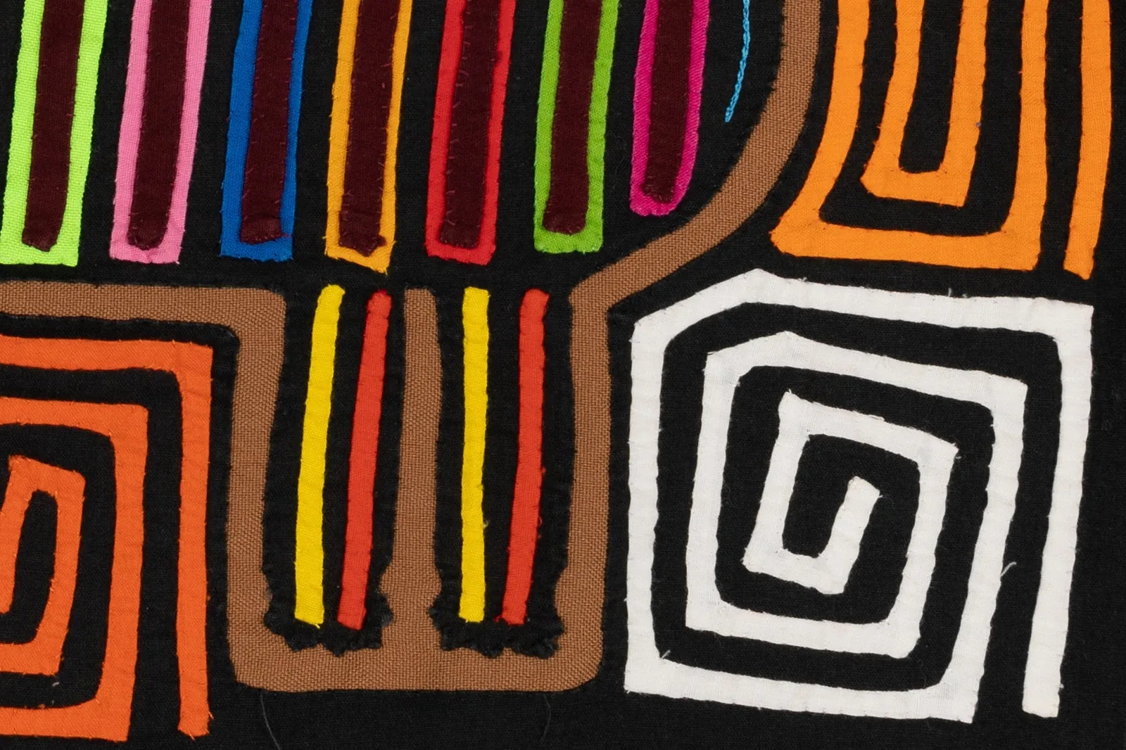 Colorful reverse appliqué design of a mola featuring vibrant lines in red, green, yellow, and orange on black fabric.