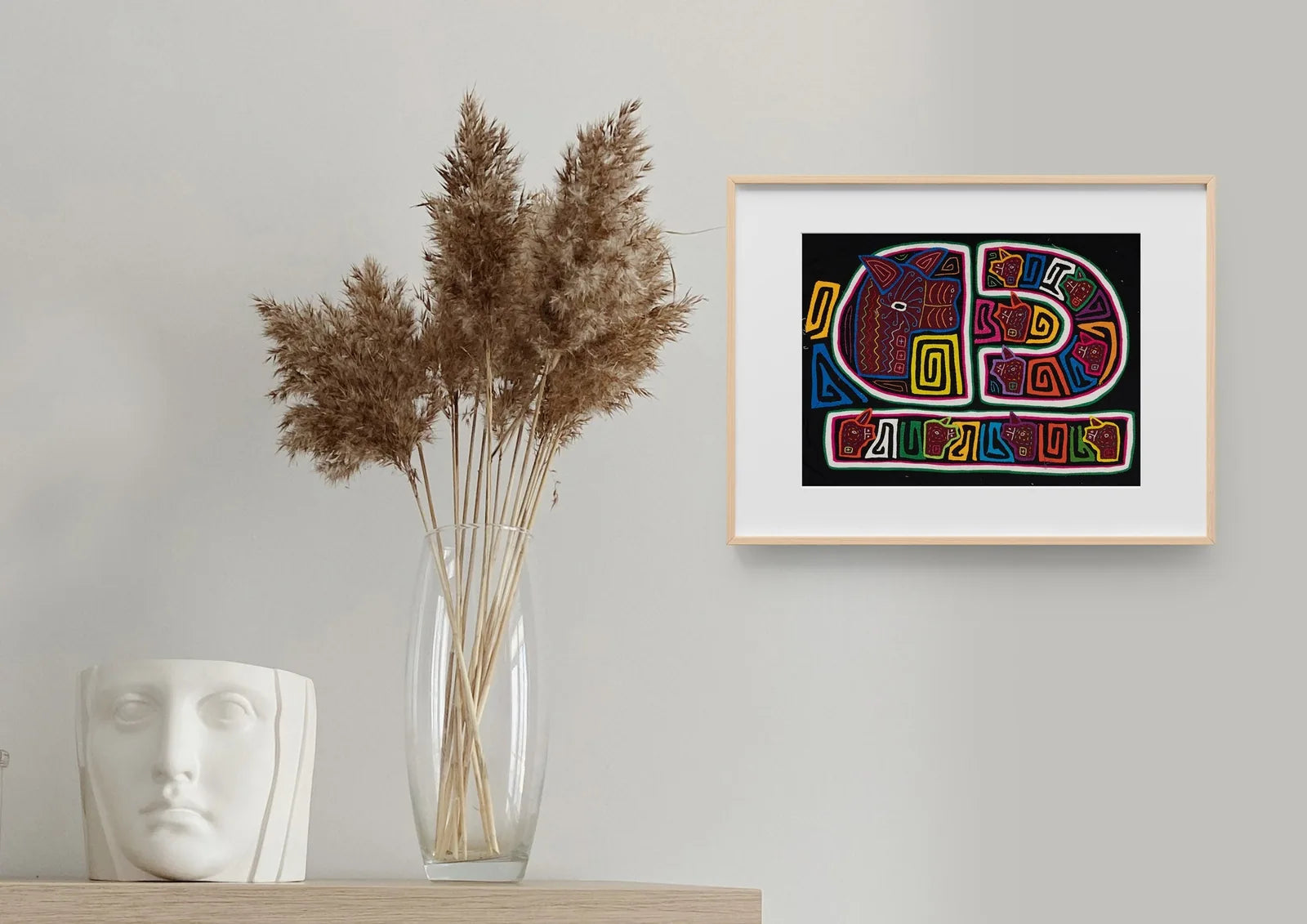 Colorful geometric designs of a dog on a black Mola textile art, framed and displayed against a neutral background.