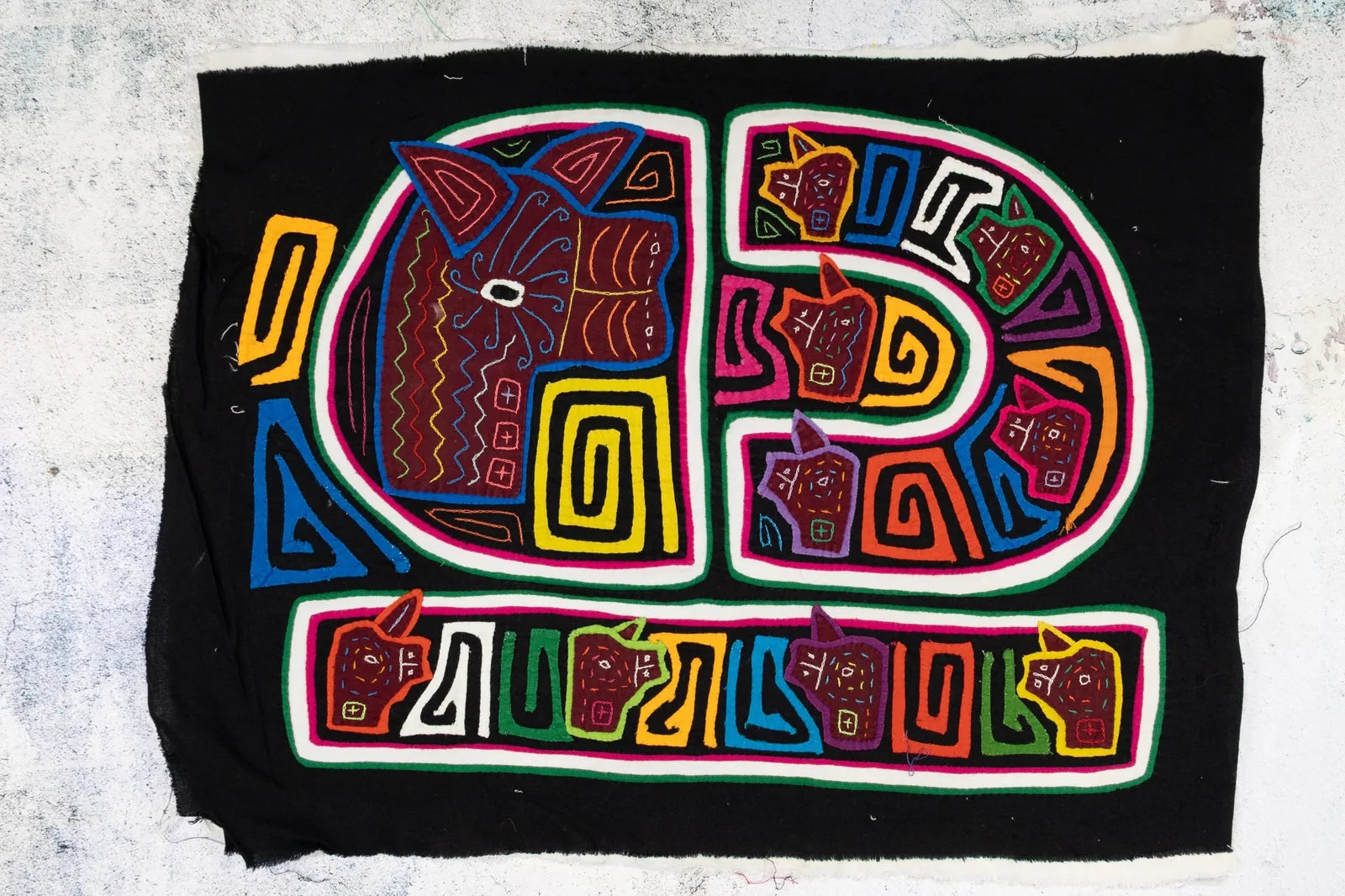 Colorful hand-stitched Mola featuring geometric dog designs on a black background, showcasing traditional Panamanian texti...
