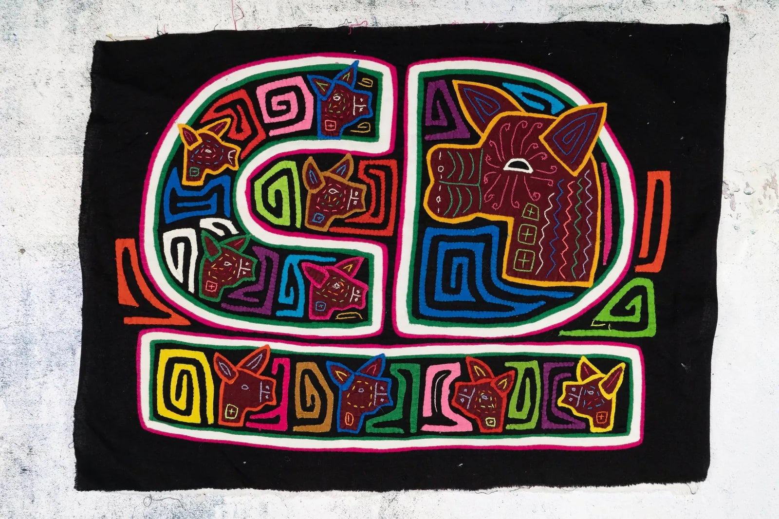Vibrant hand-stitched Mola tapestry featuring colorful dog designs on a black background, showcasing traditional Panama ar...