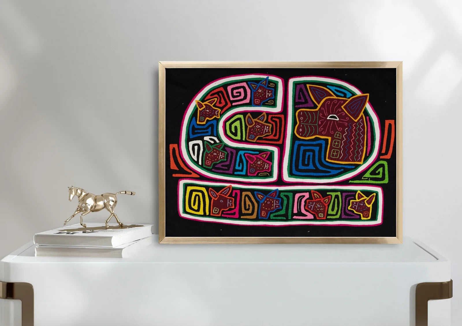Hand-stitched tapestry featuring colorful geometric patterns and dog motifs on a black background, framed and displayed.
