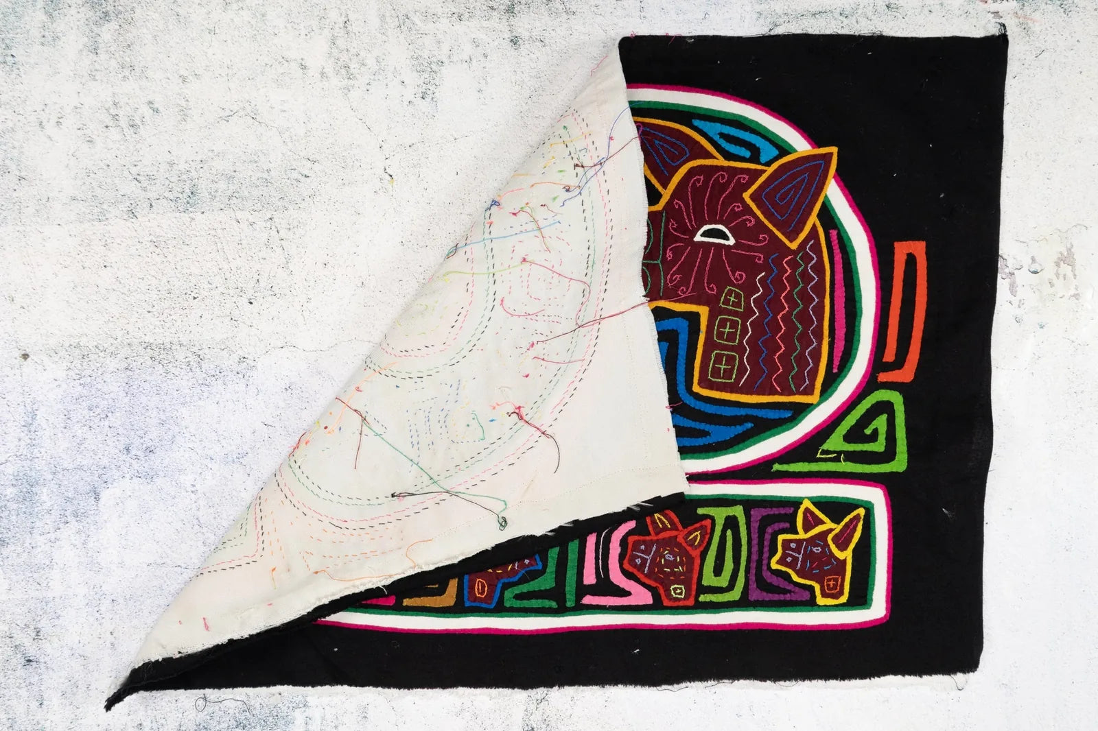 Colorful hand-stitched Mola tapestry featuring geometric dog patterns on black fabric, showcasing unique artisan craftsman...
