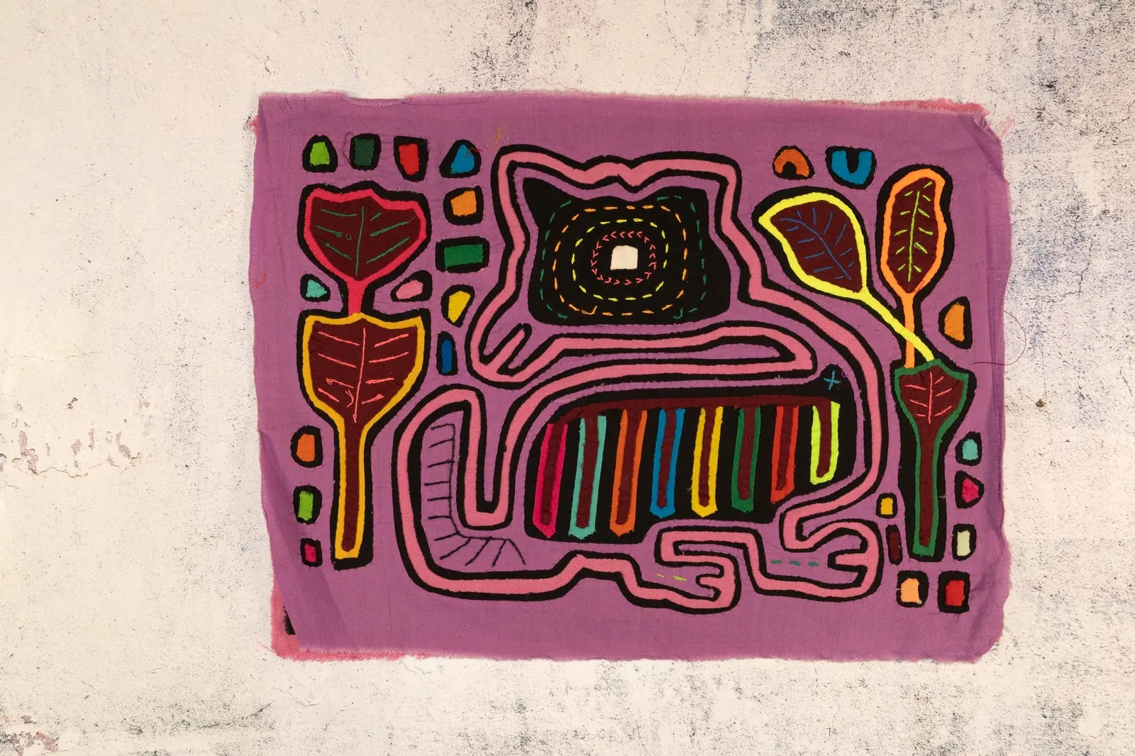 Colorful hand-stitched purple Mola featuring whimsical dog with geometric patterns and stylized leaves, made by indigenous...