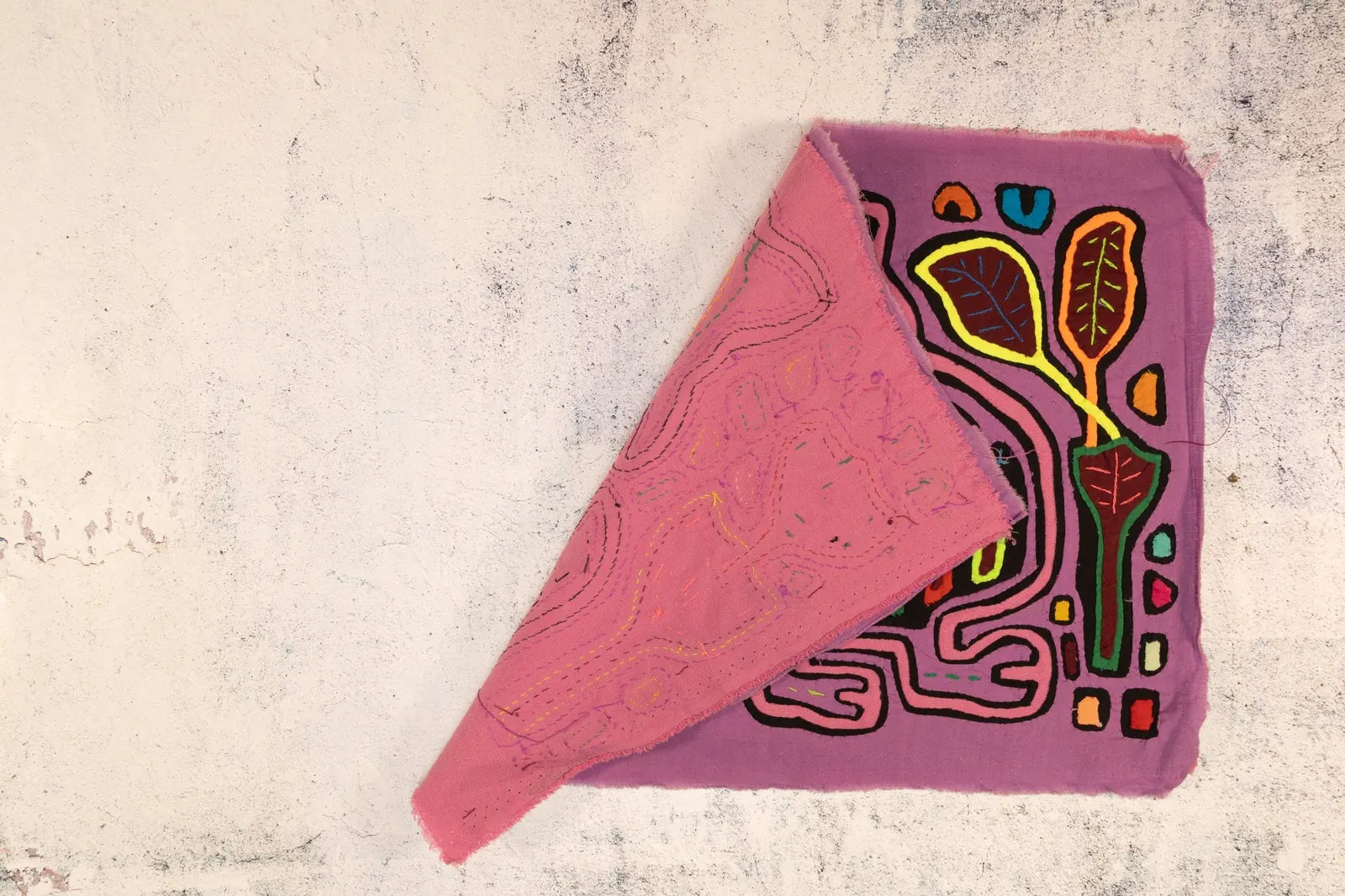 Hand-stitched purple tapestry featuring vibrant leaf and geometric patterns, showcasing unique Panamanian textile art.