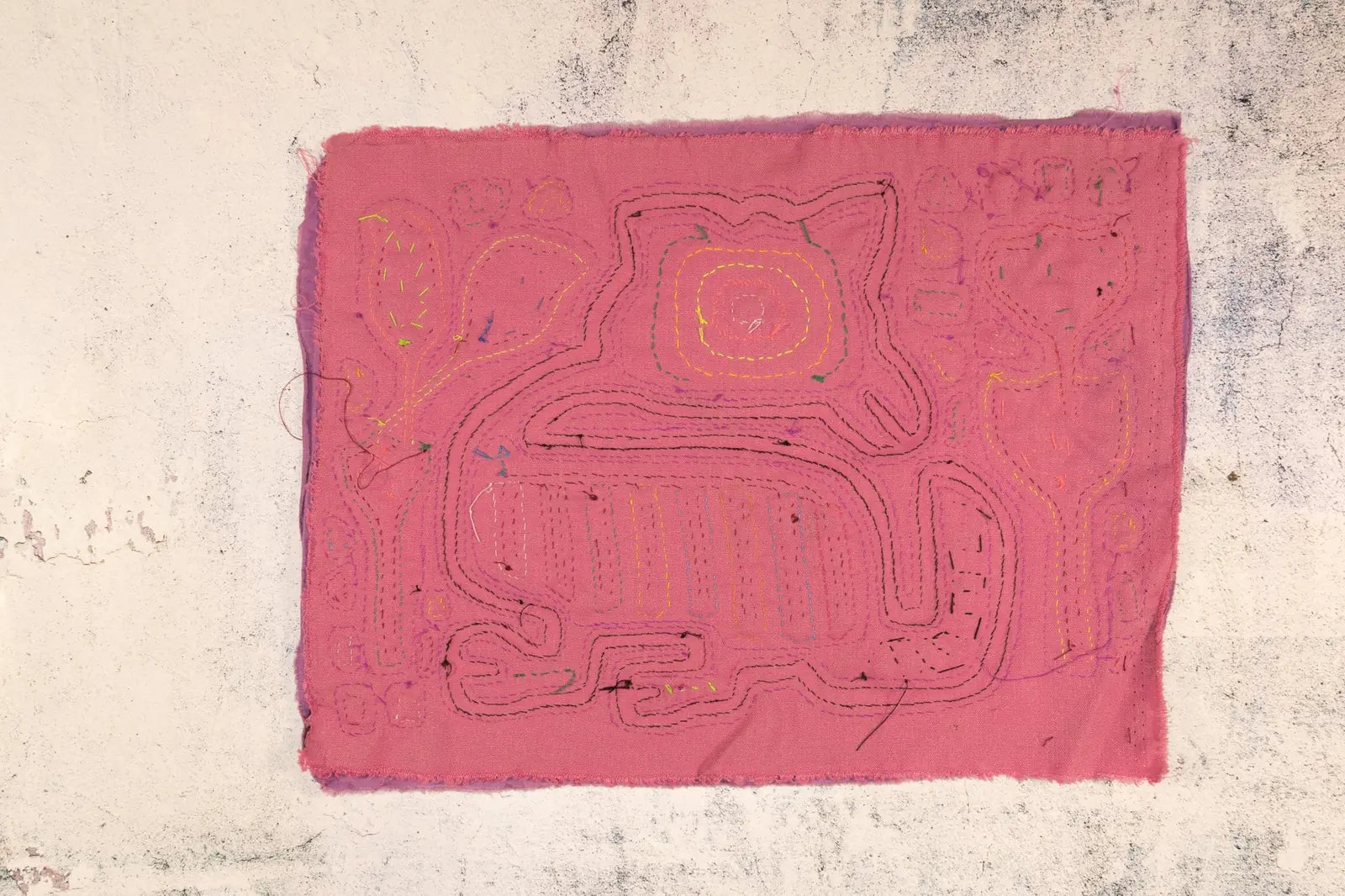 Hand-stitched pink Mola featuring a puppy design with colorful embroidery, showcasing traditional Panama textile art.