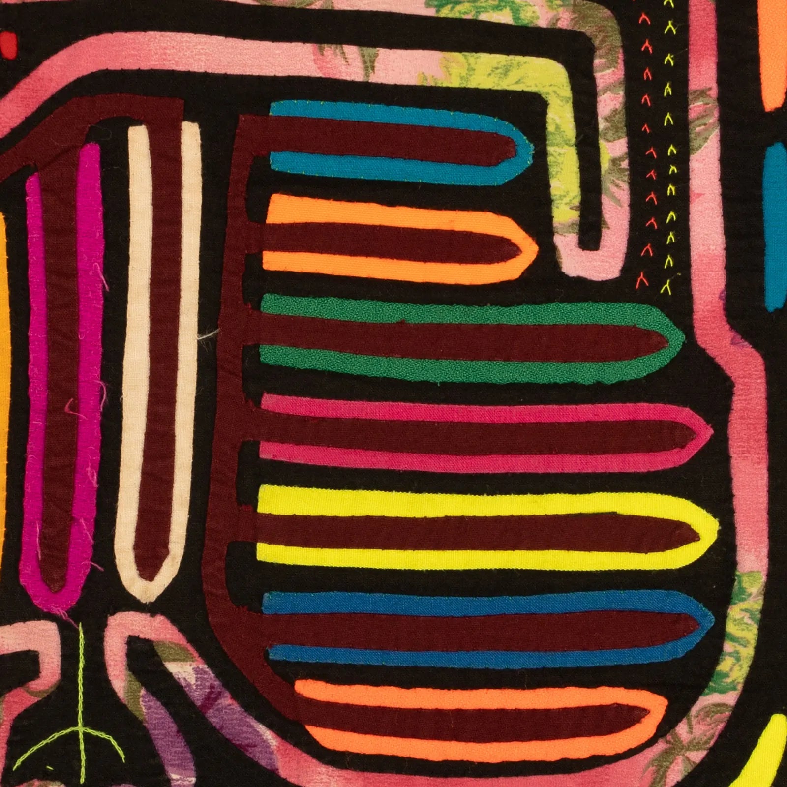 Colorful hand-stitched Mola tapestry with vibrant purple, orange, and green patterns on a black background.