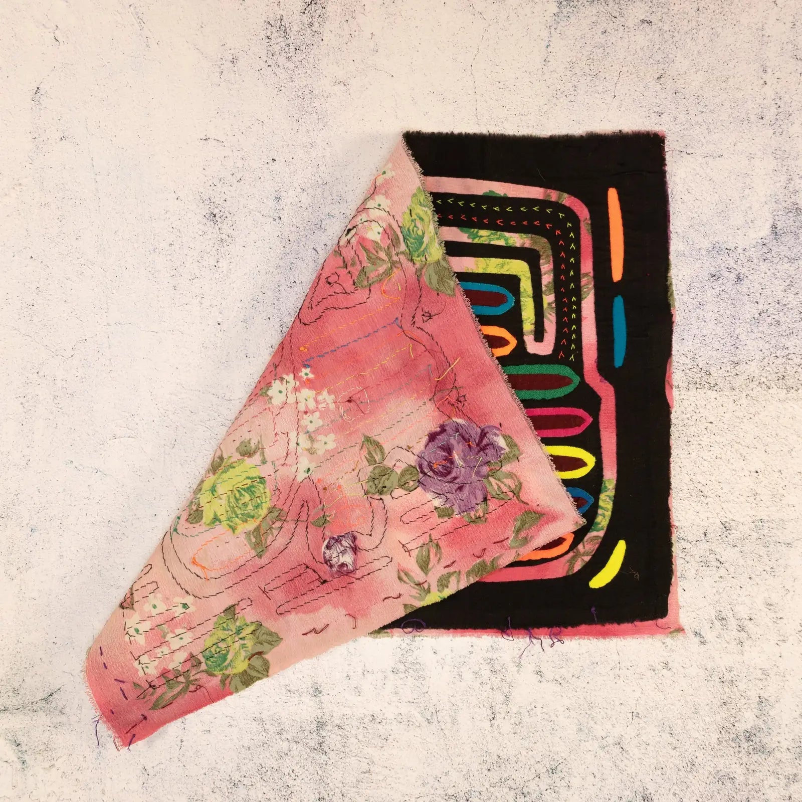 Hand-stitched purple dog Mola tapestry with vibrant floral patterns on pink background, showcasing unique textile art.