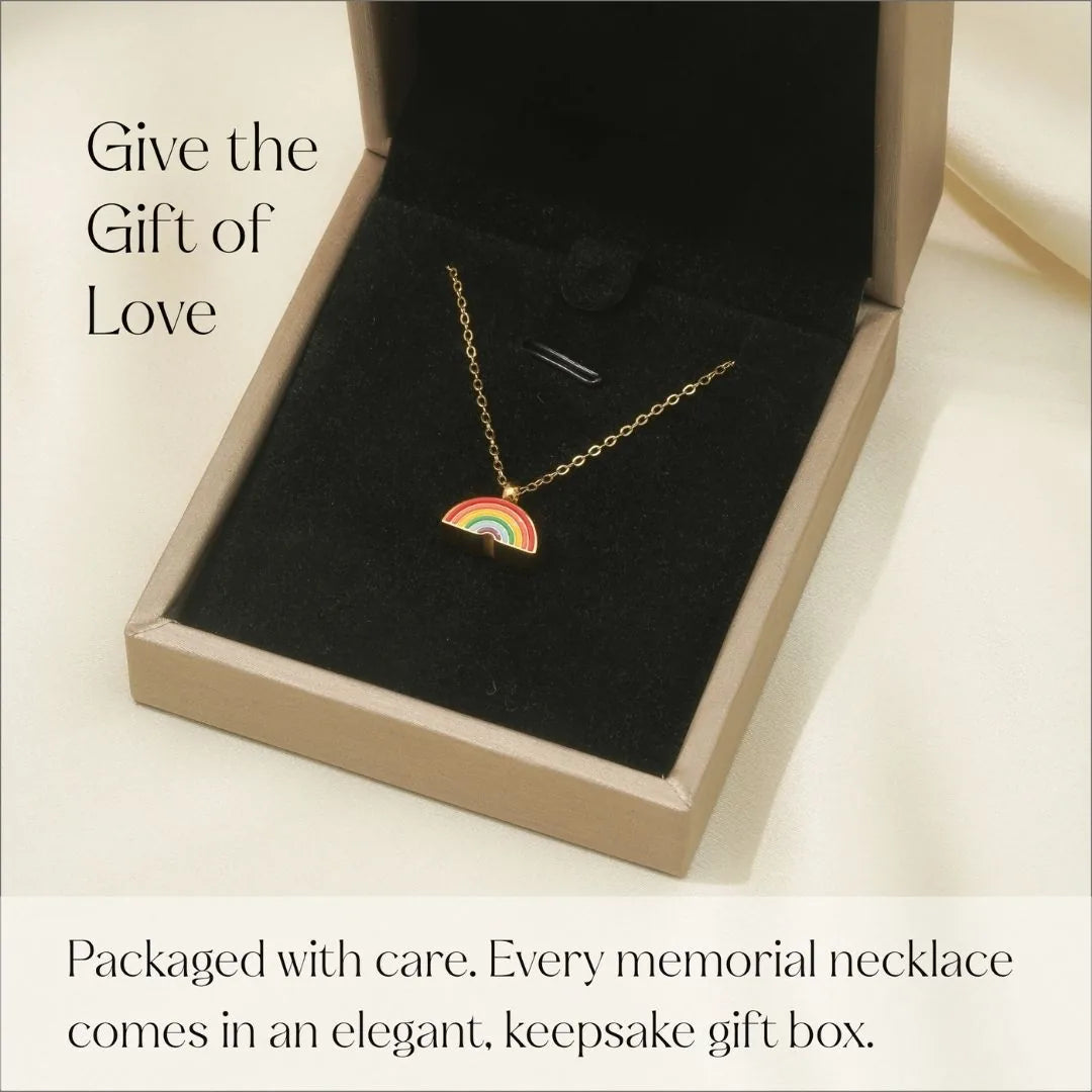 Rainbow cremation necklace with a colorful enamel design, displayed in a sleek gold keepsake box.