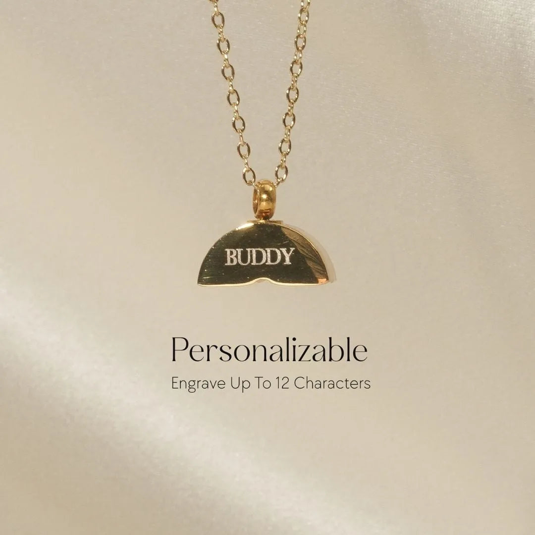 Gold memorial necklace with a half-moon pendant engraved with "BUDDY," showcasing personalization options.