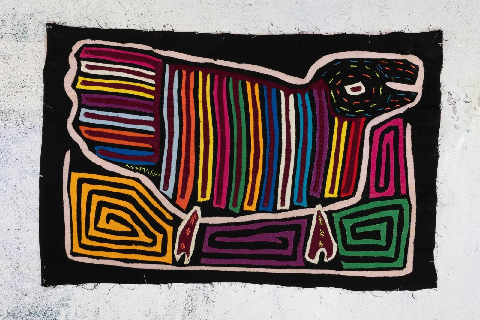 Vibrant hand-stitched Panama Mola featuring a colorful striped dog design on a black background.