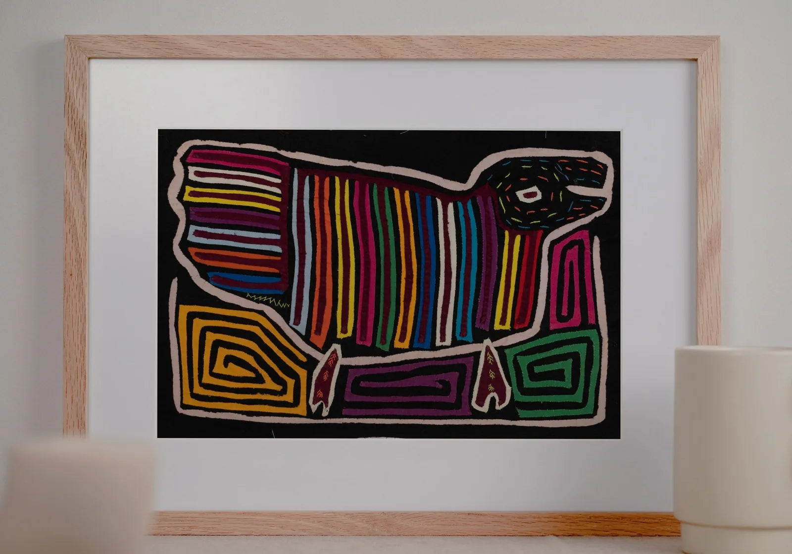 Colorful hand-stitched Mola depicting a dog with geometric patterns on a black background, framed elegantly.
