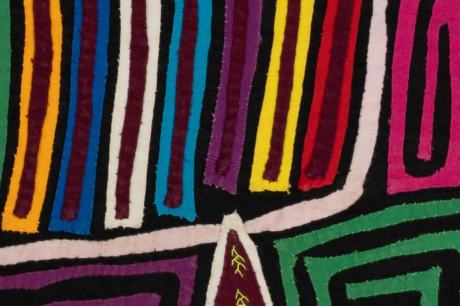 Colorful hand-stitched textile featuring geometric patterns in red, blue, yellow, and green on a black background.