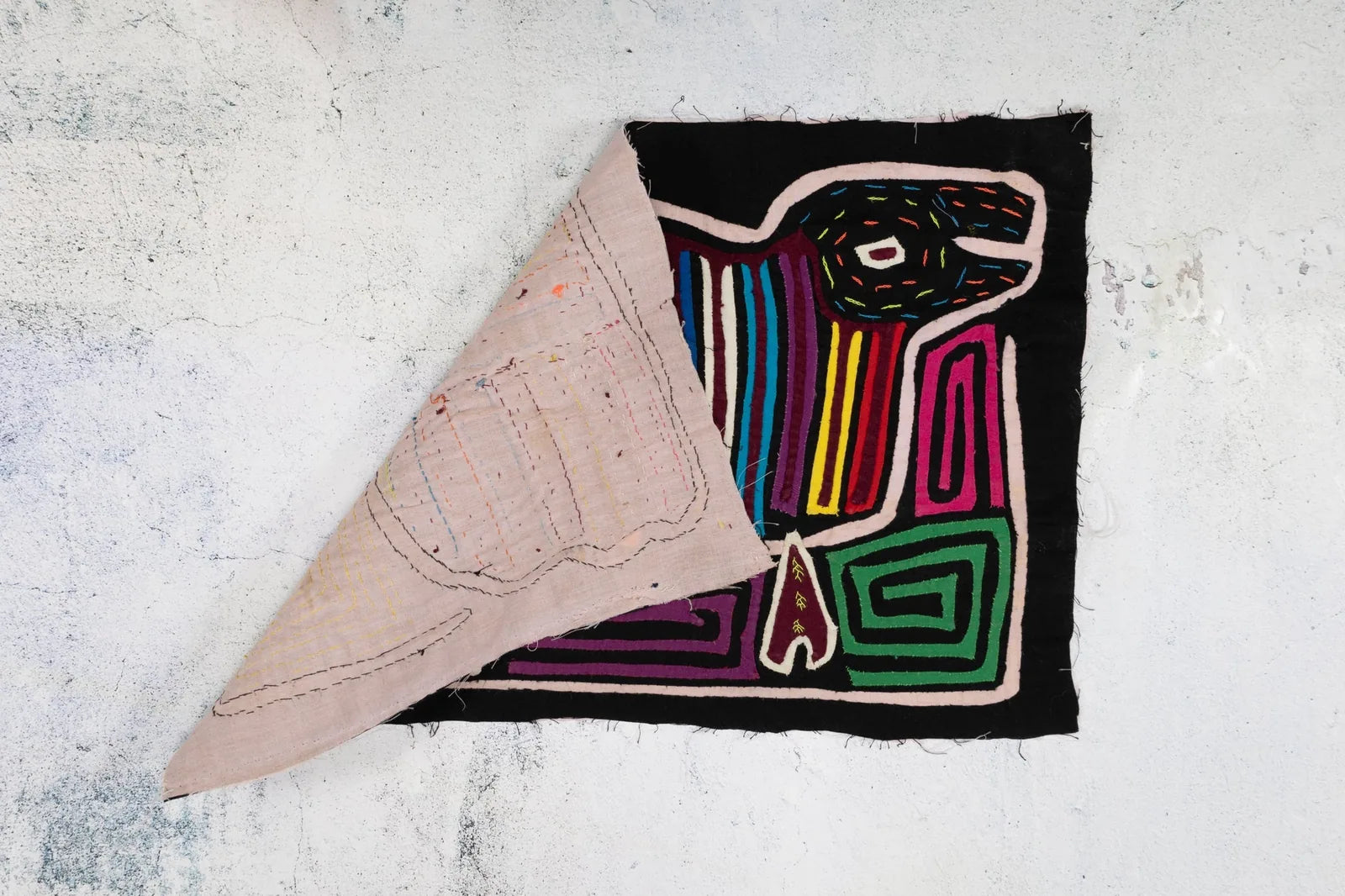 Rainbow puppy design on hand-stitched black fabric, featuring colorful geometric patterns. Perfect for decorative use.