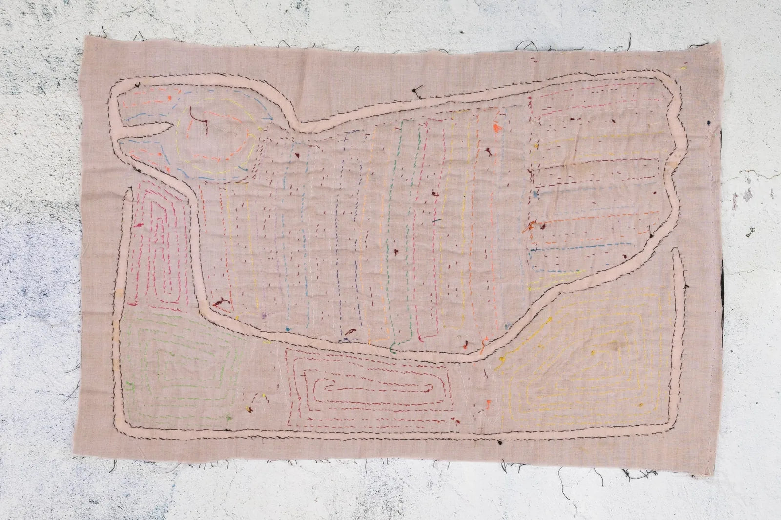 Hand-stitched Panama Mola featuring a colorful geometric design on a textured, peach background.