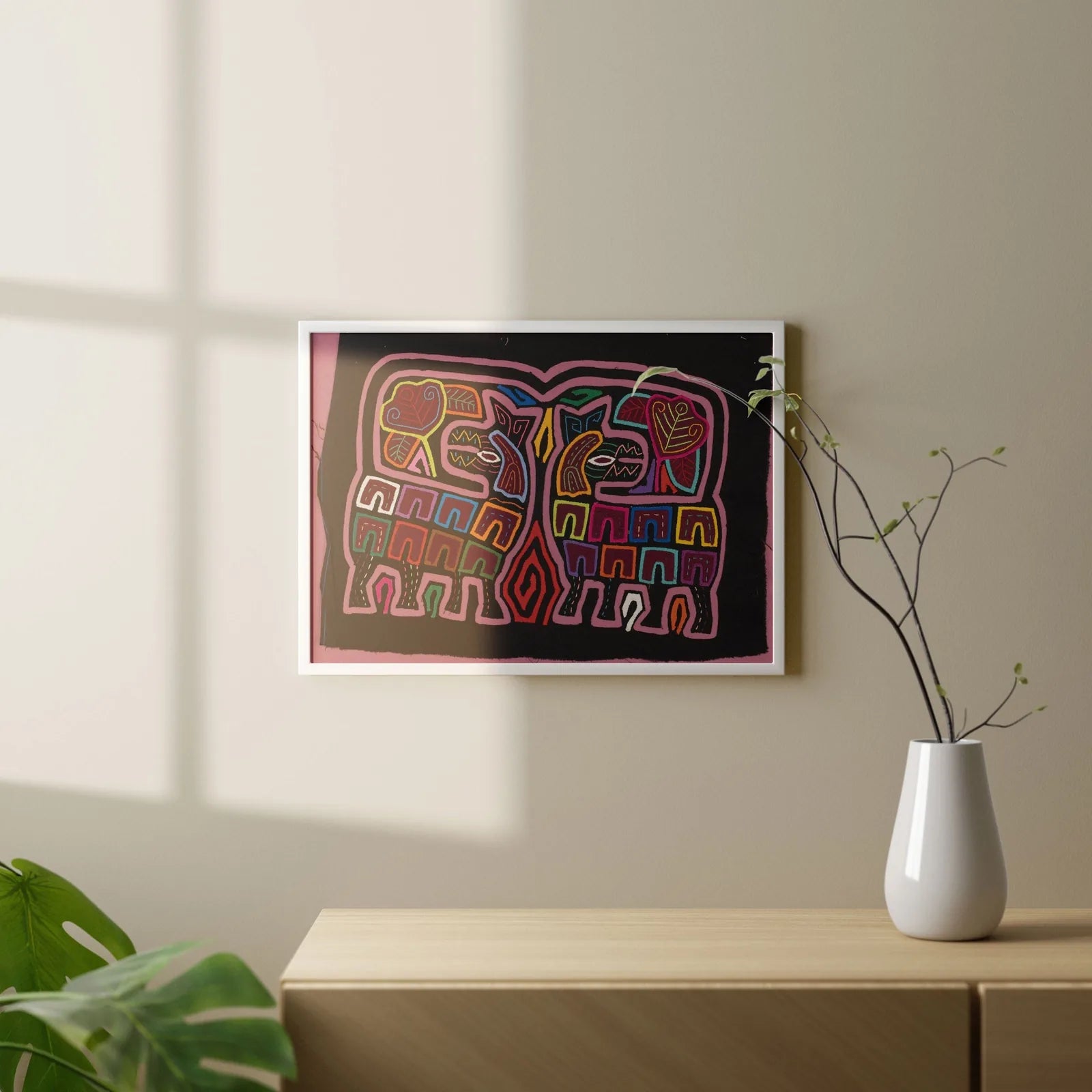 Colorful geometric elephant design in hand-stitched Mola textile art, framed on a wall against a soft-lit background.