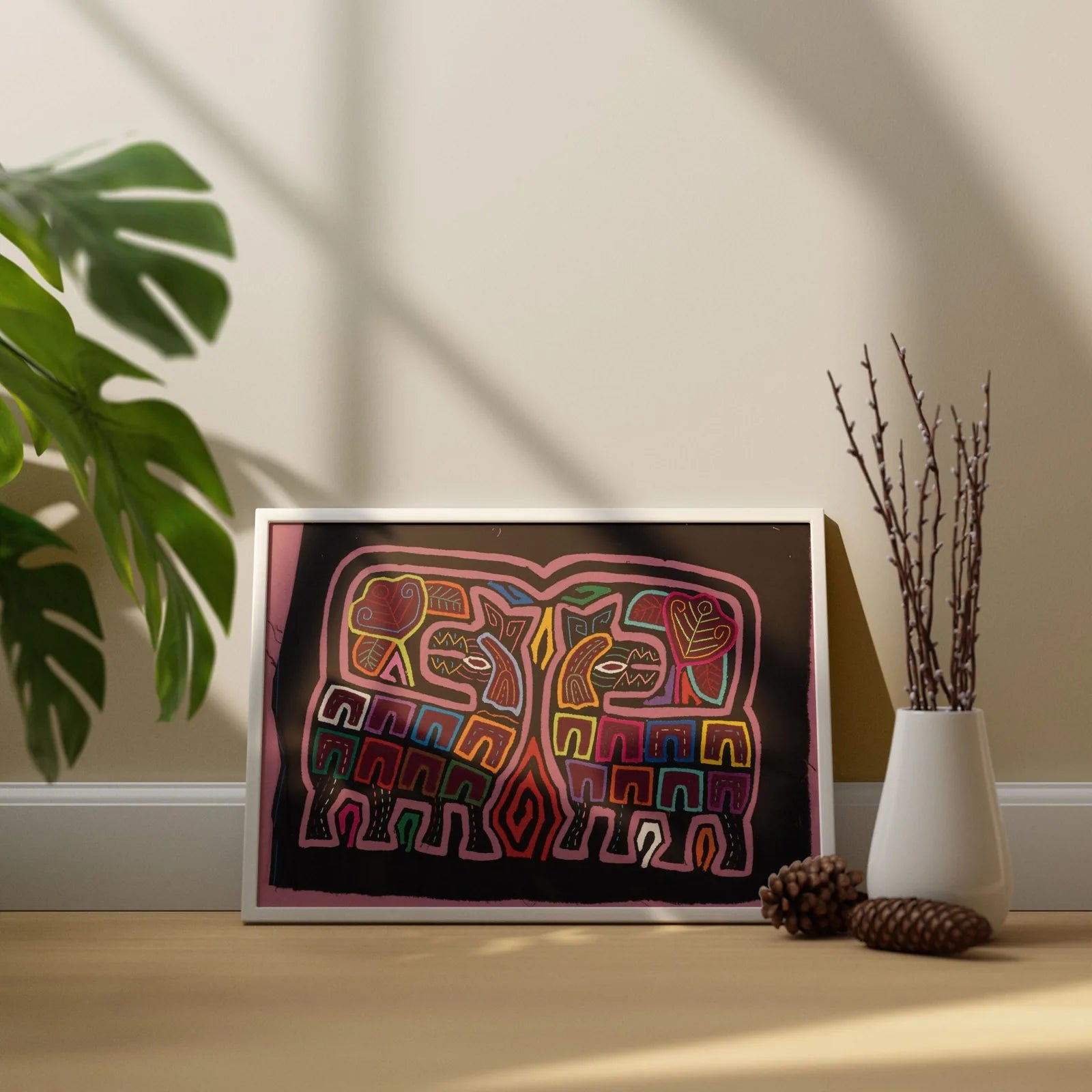 Colorful abstract Mola artwork featuring geometric animal shapes on a dark background, framed and displayed with decor.