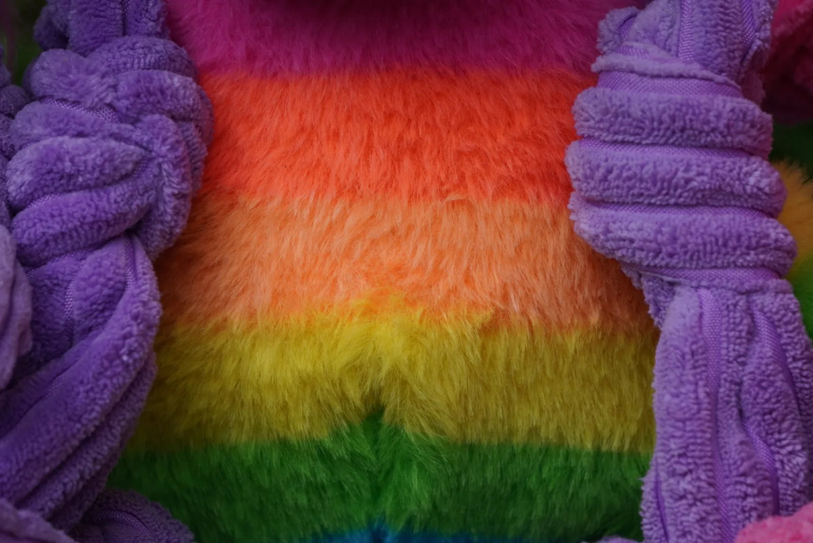 Colorful plush fabric featuring rainbow stripes in vibrant hues, with a soft purple knotted limb design.