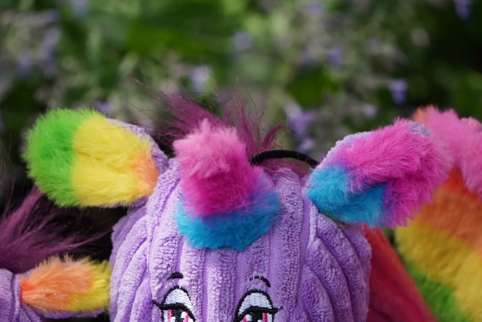 Colorful plush ears of a purple unicorn toy with rainbow accents, showcasing soft fur and a playful design.