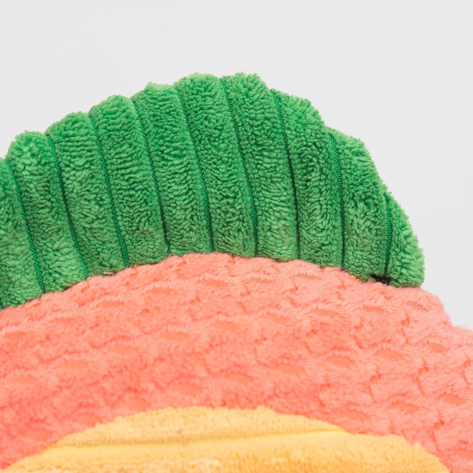 Colorful plush dog toy with a green, ridged top, and soft, textured pink and yellow body for safe play and cuddling.