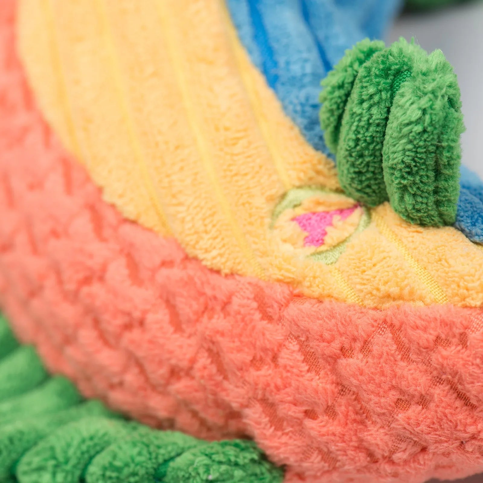Colorful plush Rauccous Rainbow Trout Knottie® toy showcasing soft textures in vibrant yellow, pink, and blue, designed fo...