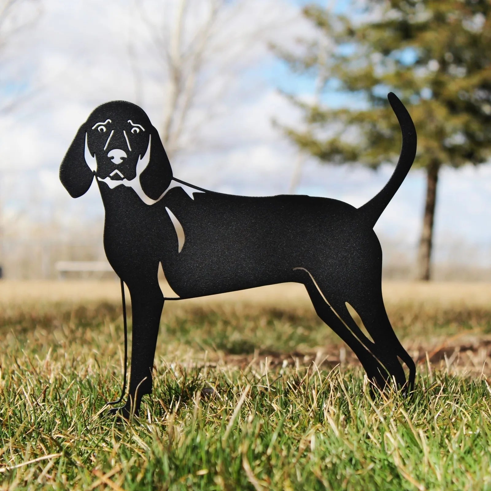 Black metal silhouette of a Redbone Coonhound standing on grass, featuring detailed design and rustic charm.