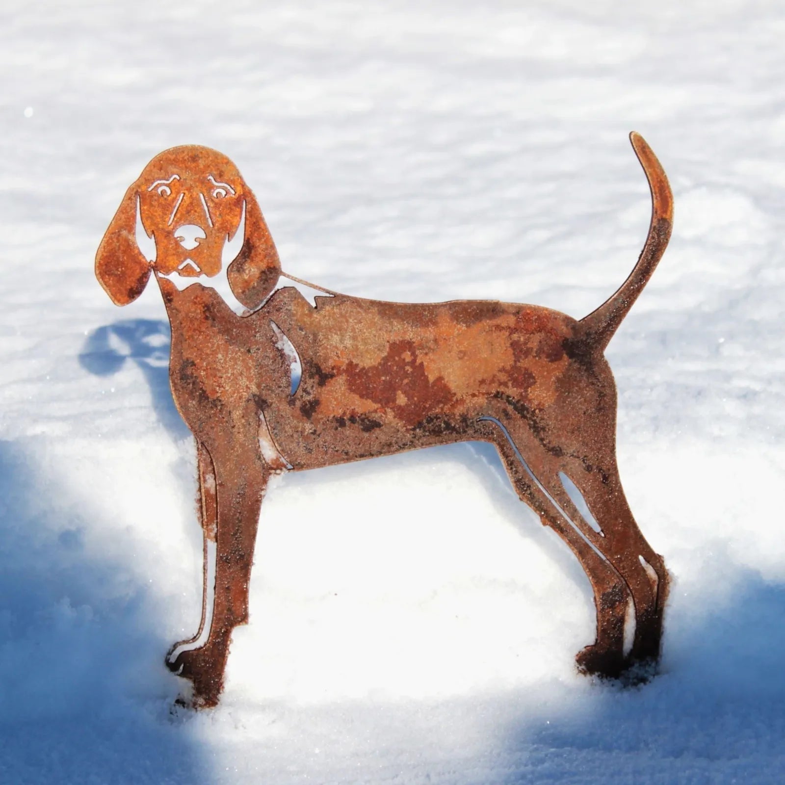 Rusty metal silhouette of a Redbone Coonhound stands in snow, showcasing its intricate design and weathered texture.